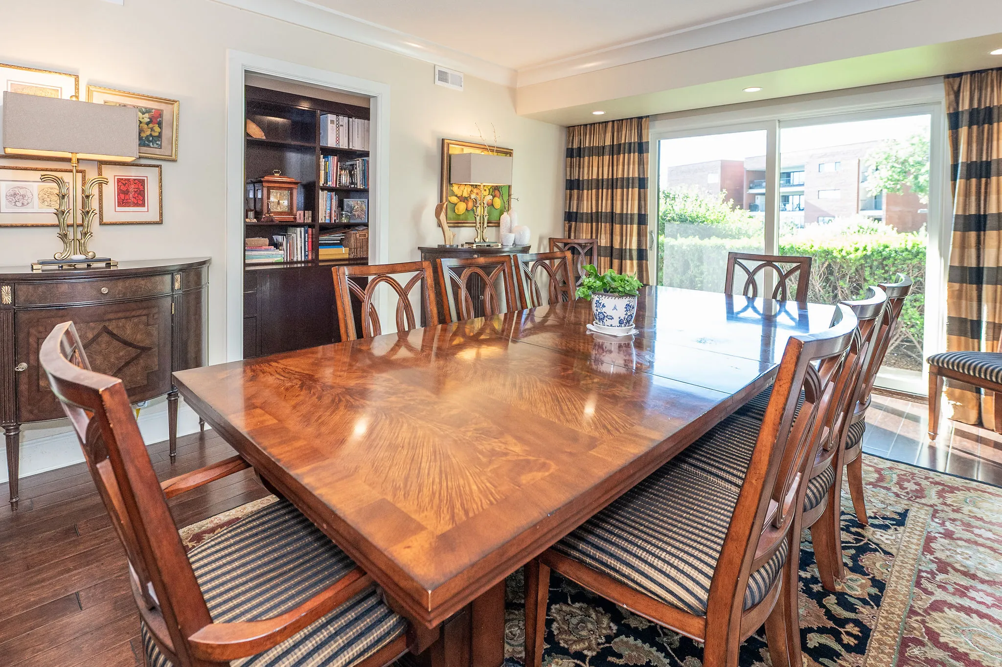 Expansive room featuring rich wood-finish flooring, a built-in shelving unit, and crown molding