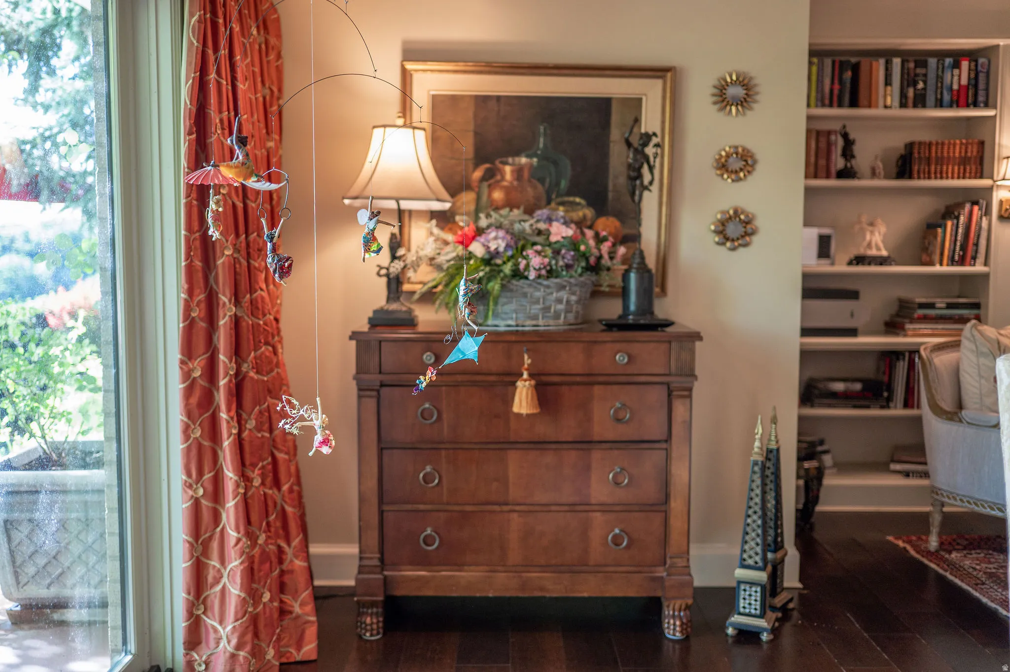 Dark wood-finish flooring complements the built-in shelving and custom drapery
