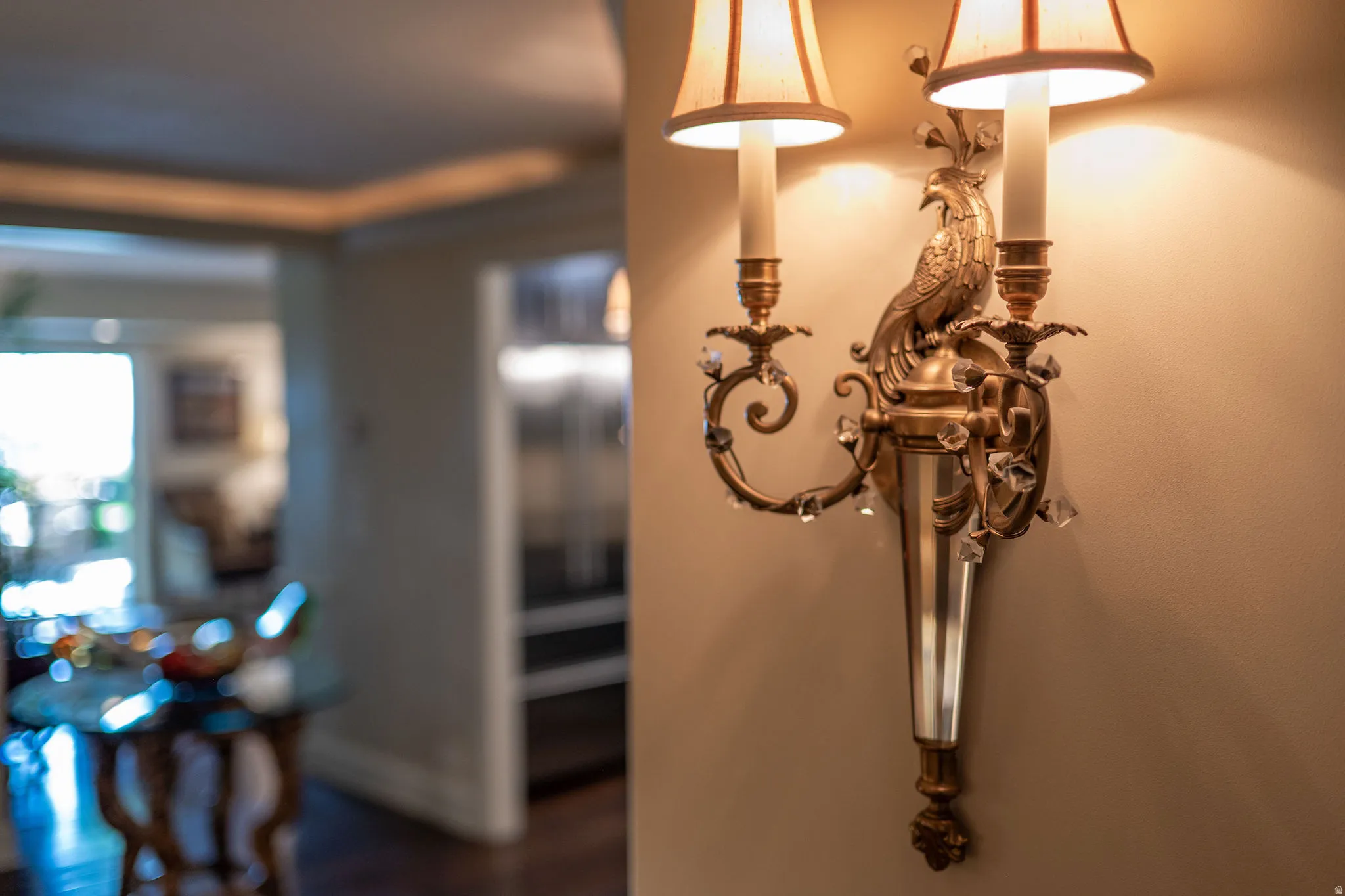 Ornate brass wall sconce with a decorative bird motif and crystal accents