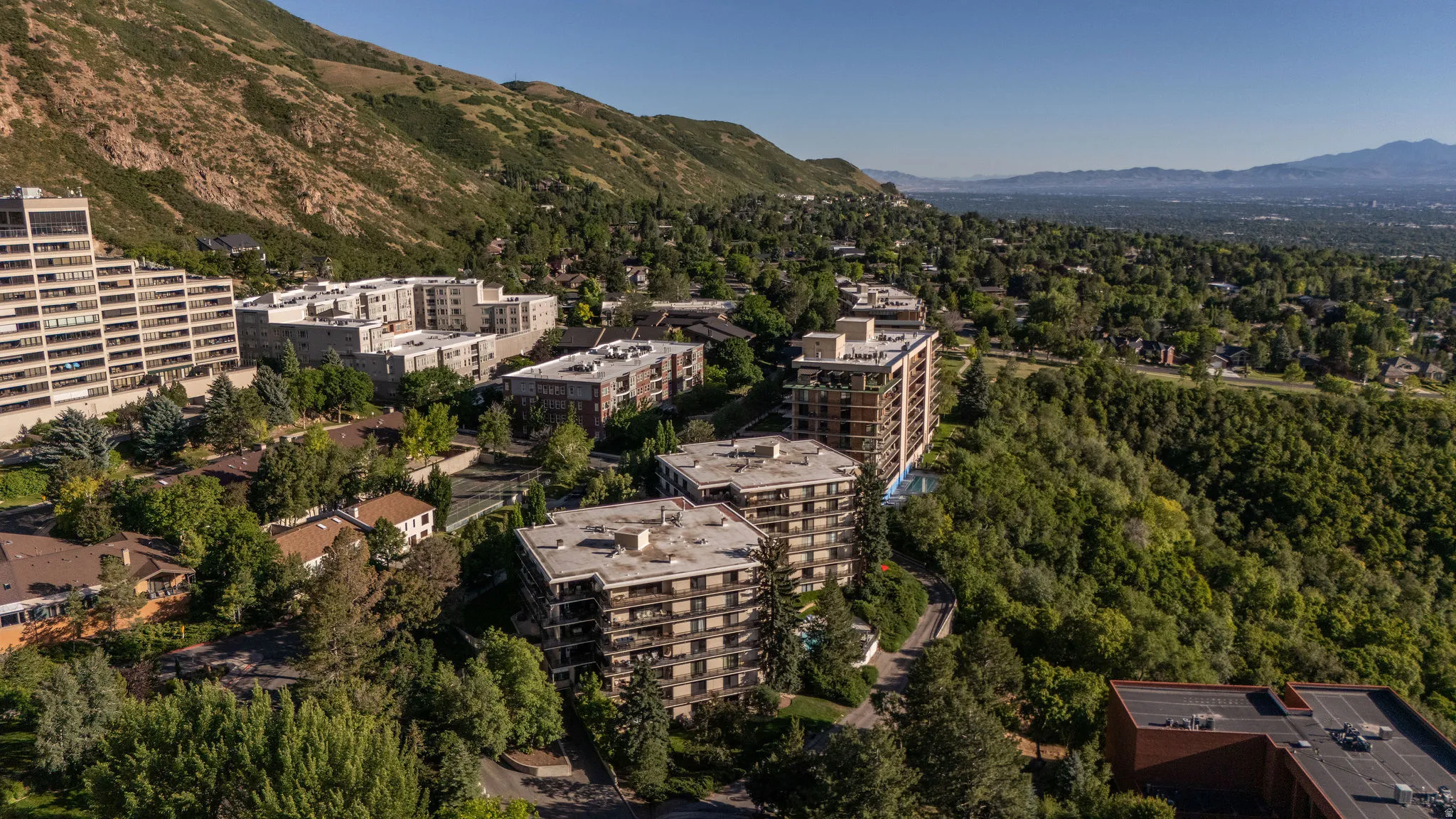 Aerial perspective showcasing multiple multistory residential buildings nestled into a verdant mountainside