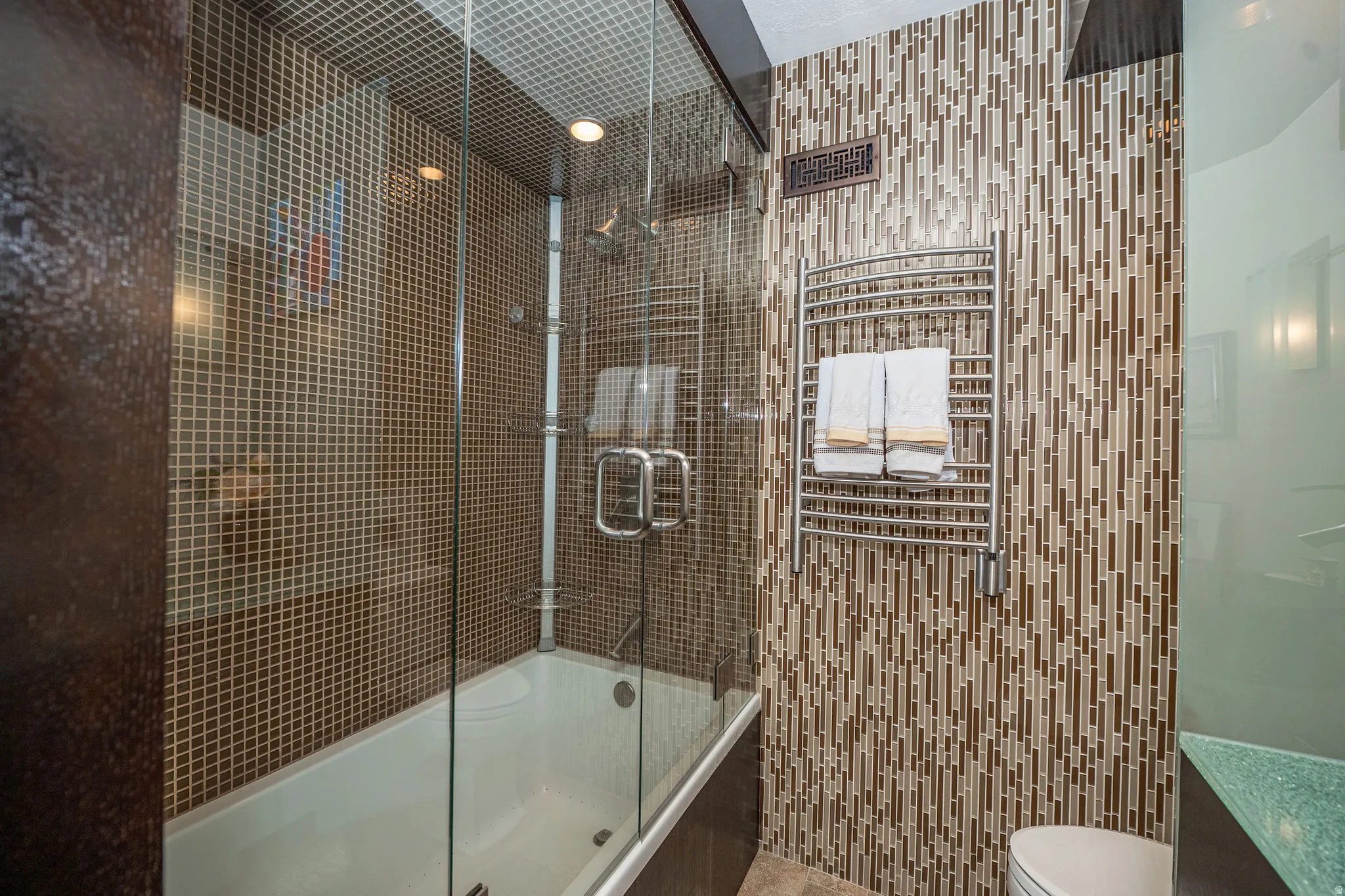 Tiled bath and shower combination with a frameless glass enclosure