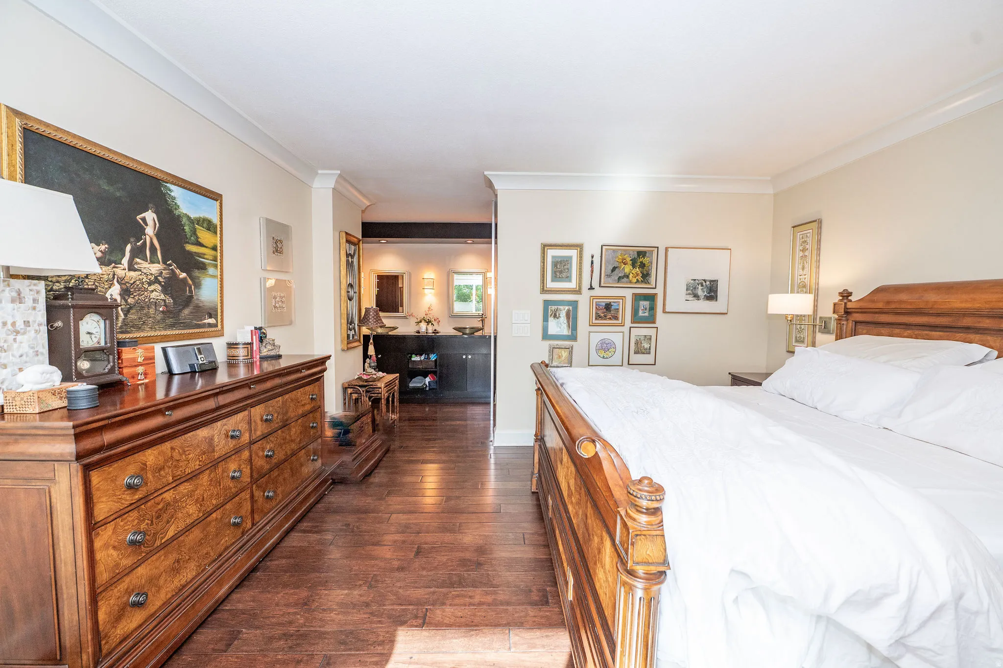 Spacious bedroom featuring wood-finish flooring, crown molding, and a warm neutral color palette