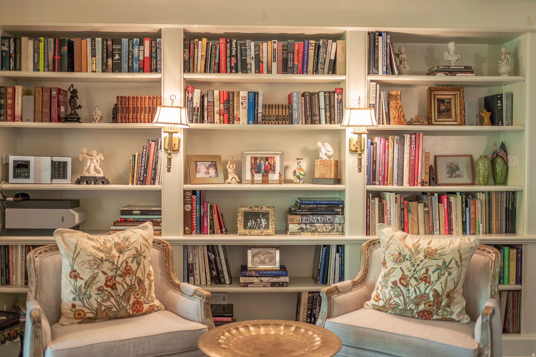 Built-in shelving unit featuring integrated wall sconces, multiple display shelves, and a polished brass-tone accent table