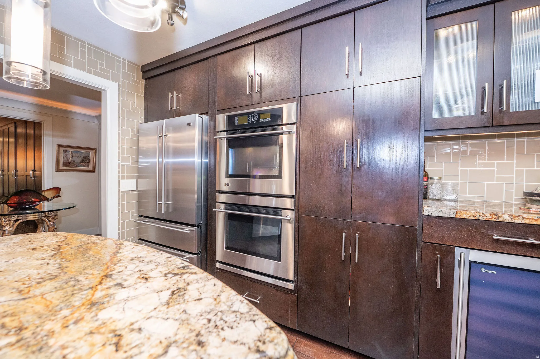 Kitchen featuring dark wood-finish cabinetry, stainless steel appliances, a built-in double oven, and a beverage cooler