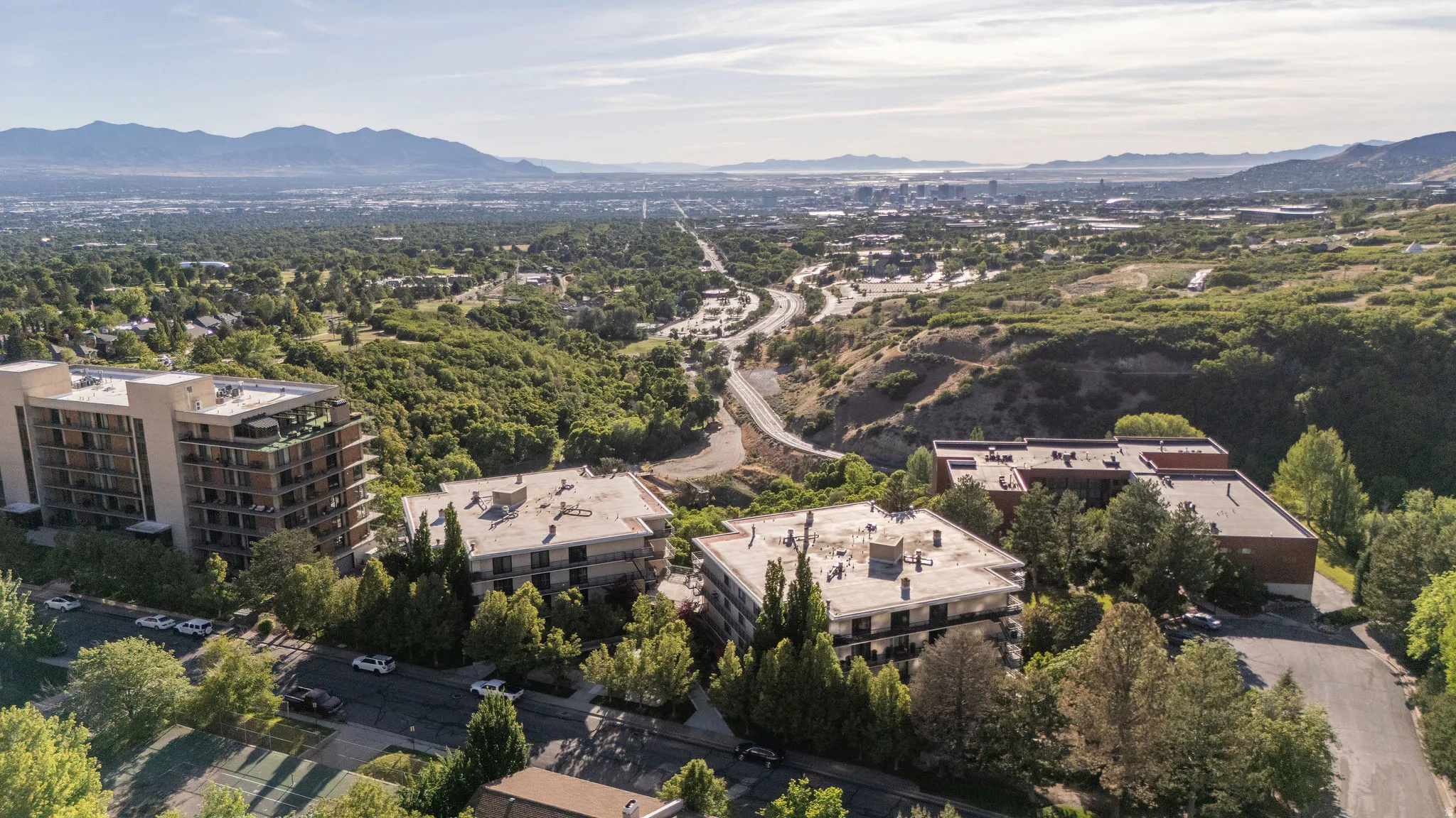 Expansive mountain and city scenery with multiple buildings surrounded by mature trees