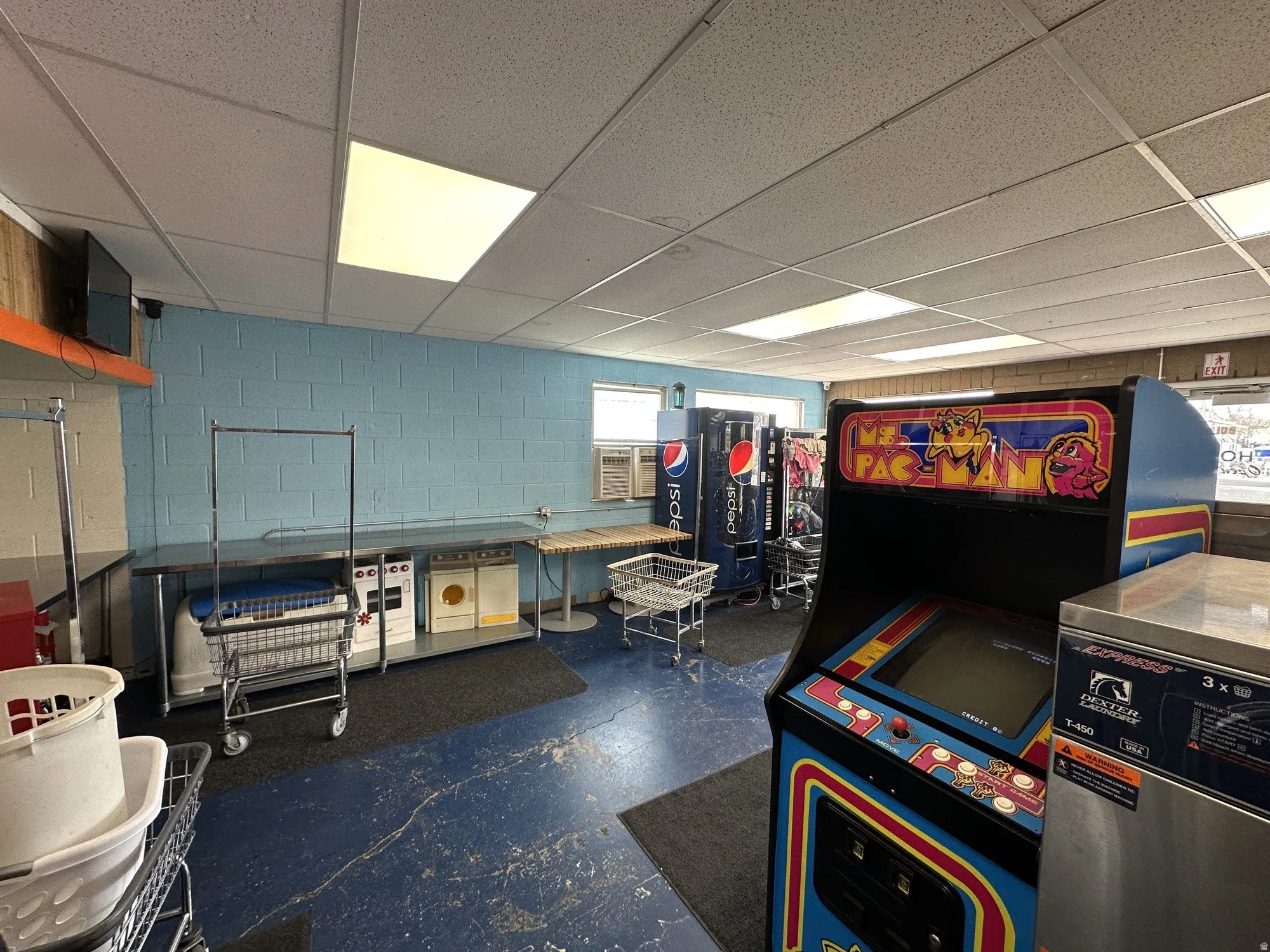 Spacious interior with blue block walls, drop ceiling, and fluorescent lighting