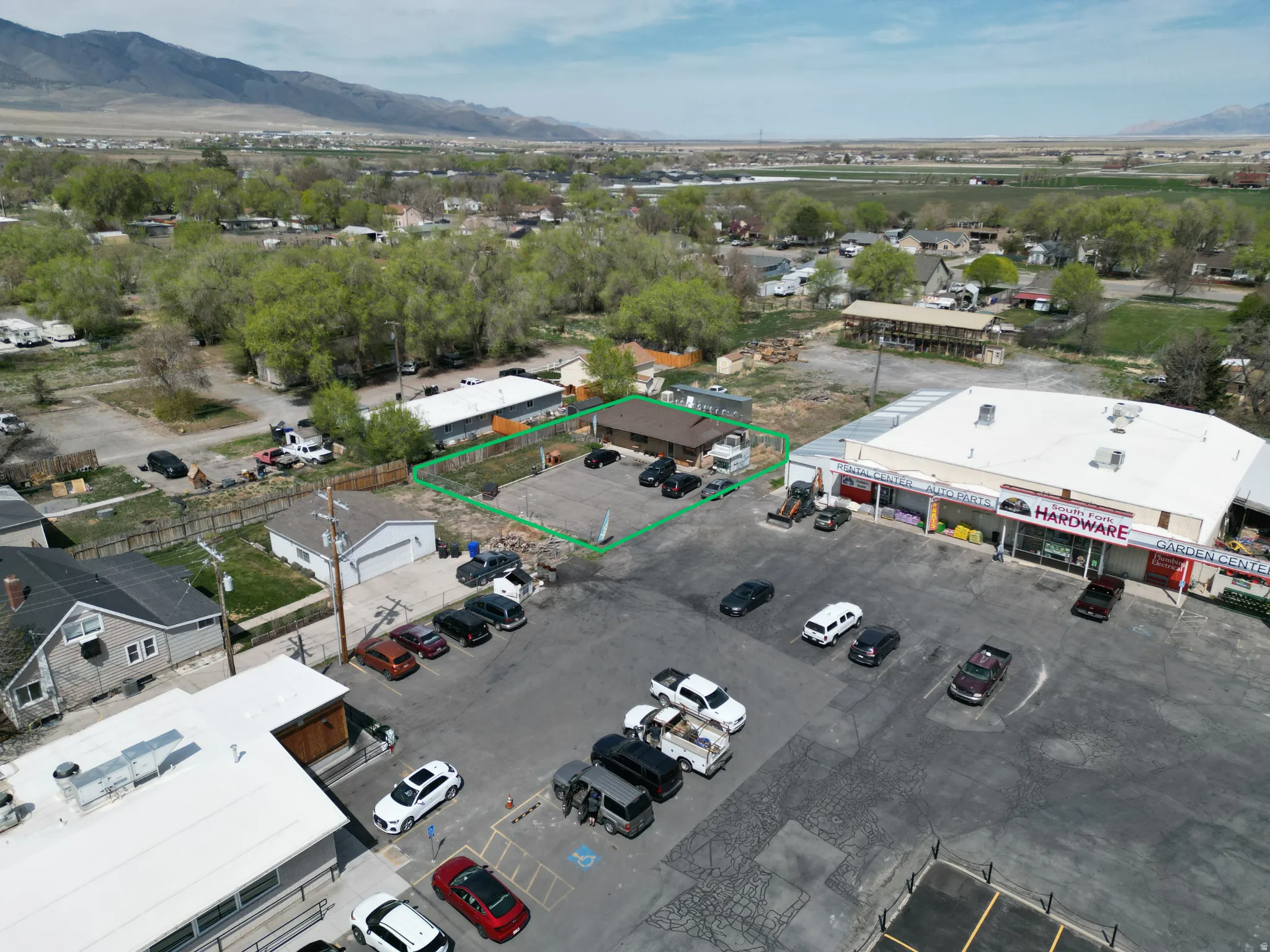 Commercial property featuring an asphalt parking area, adjacent retail building, and a fenced perimeter