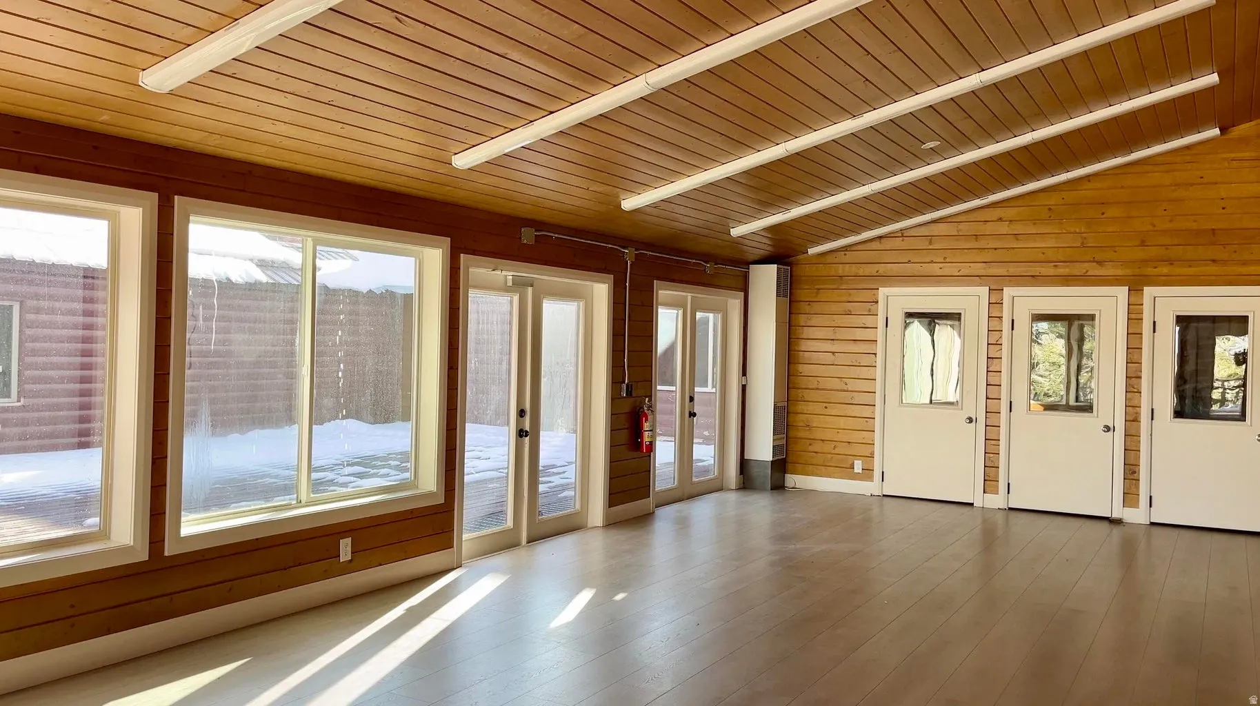 Vaulted ceiling with wood paneling and linear fluorescent lighting