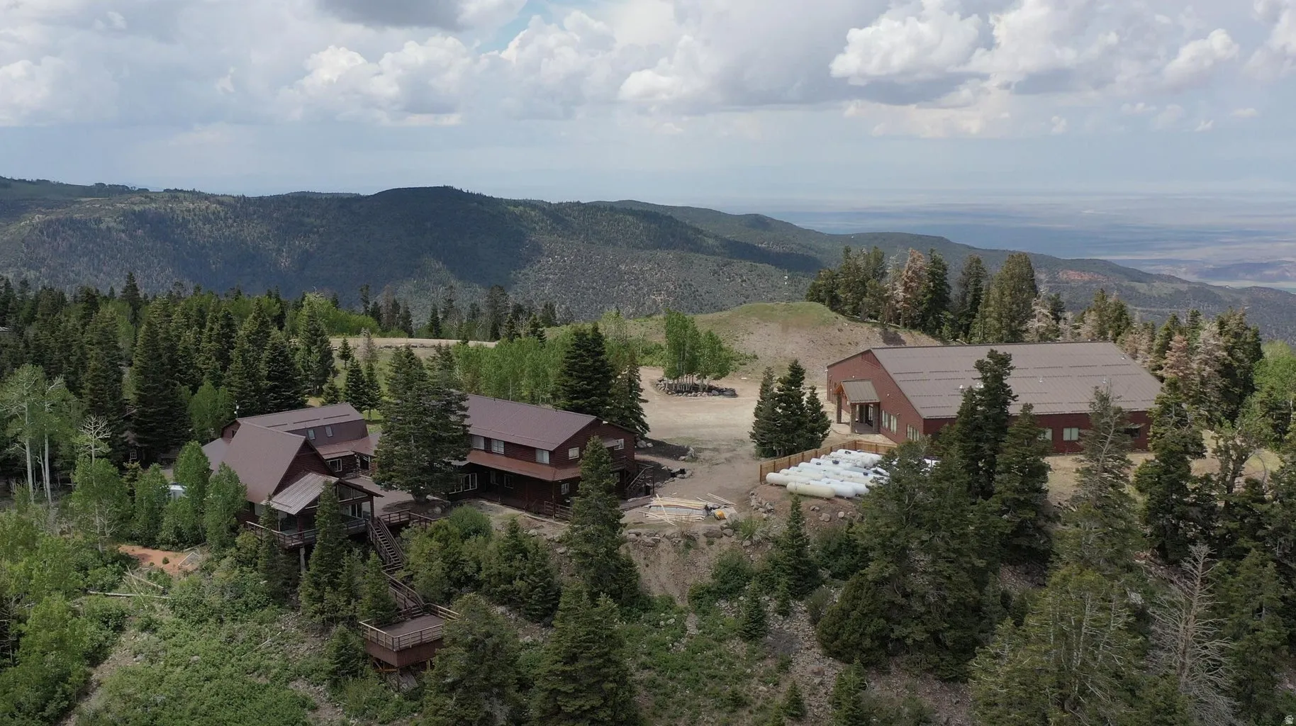 Mountain property featuring multiple structures, including two multi-story buildings with brown exteriors and dark roofs