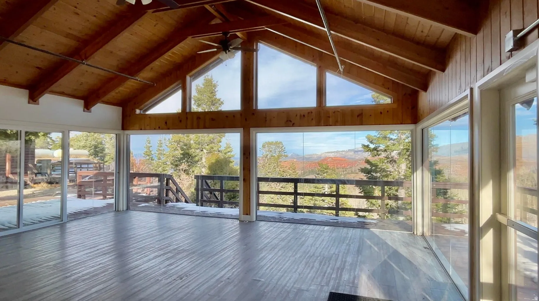 Spacious room featuring wood-finish flooring and a wood-paneled vaulted ceiling with exposed beams