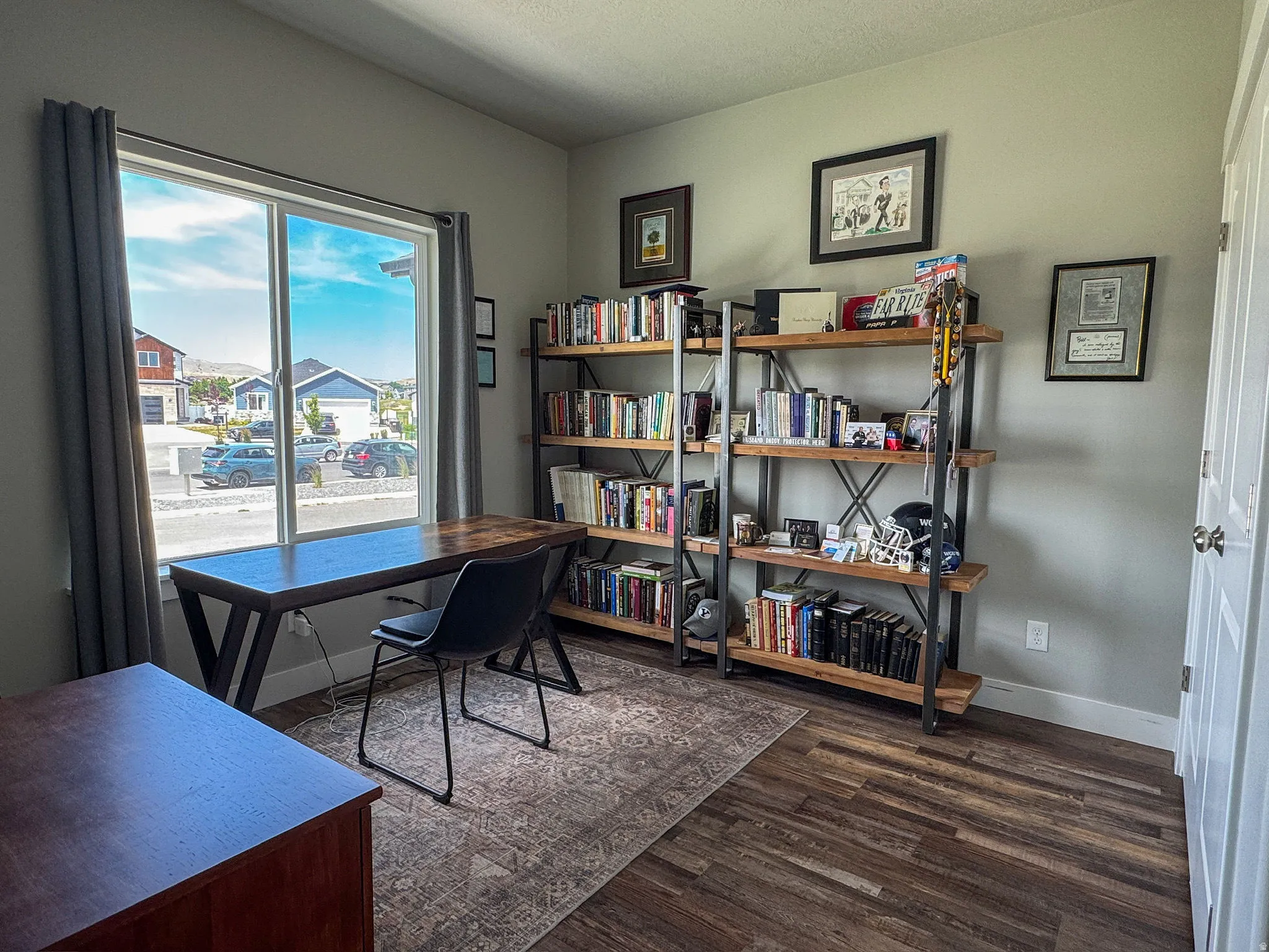 Versatile interior space featuring wood-finish flooring, a large window, and a built-in shelving unit