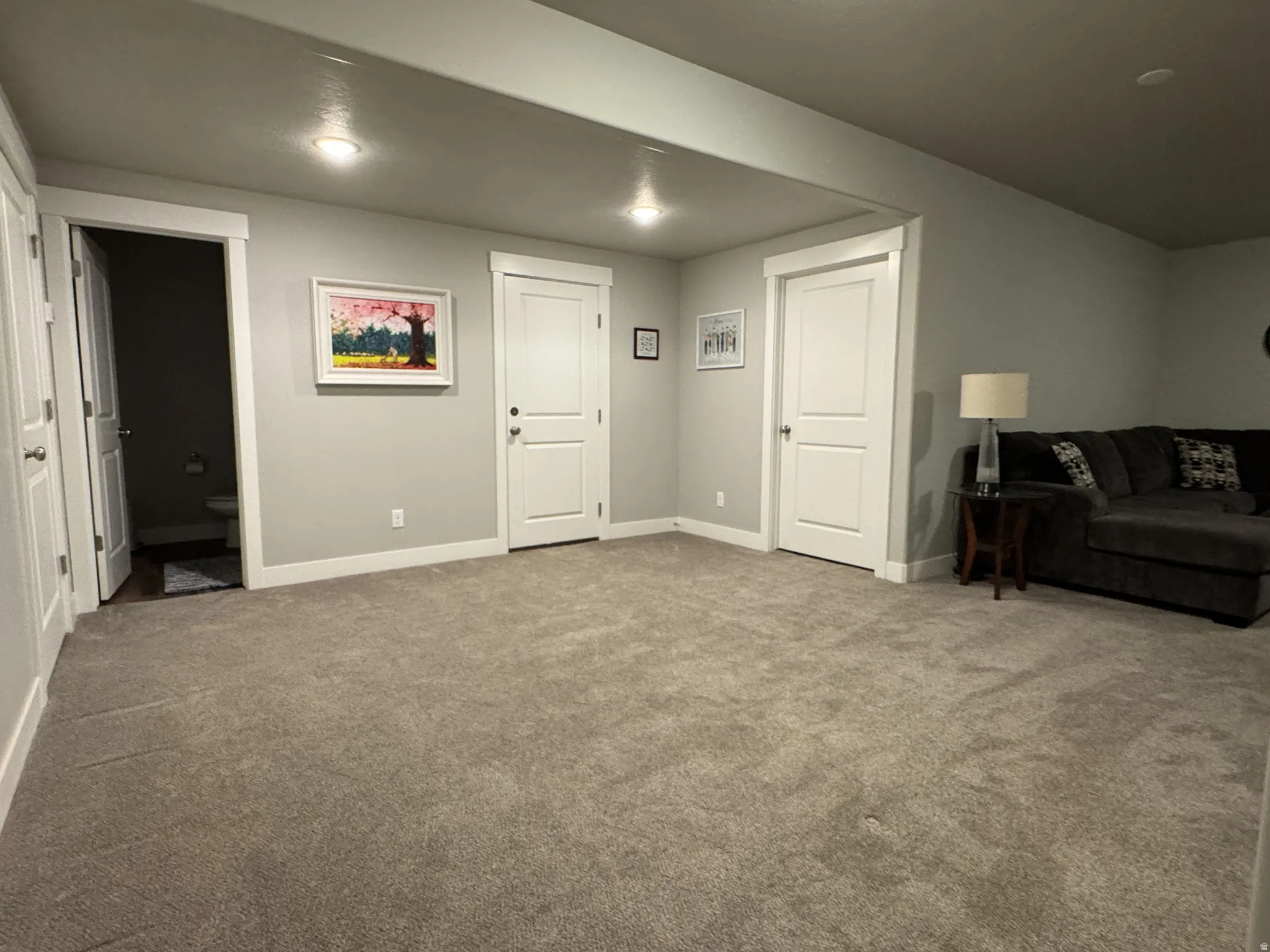 Spacious carpeted area with recessed lighting and neutral wall tones