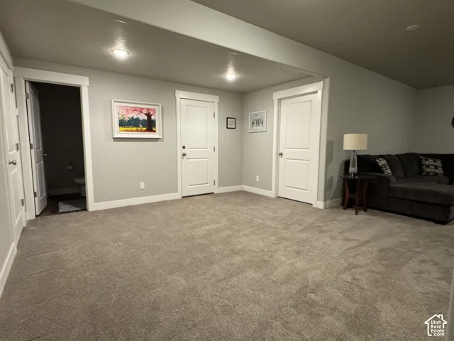 Spacious carpeted area with recessed lighting and neutral wall tones