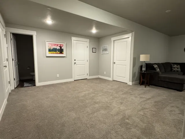 Spacious carpeted area with recessed lighting and neutral wall tones