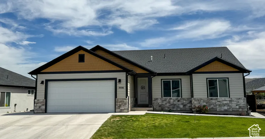 Exterior facade featuring horizontal lap siding, shingle-style accents in the gables, stone veneer base, asphalt shingle roof, and a concrete driveway