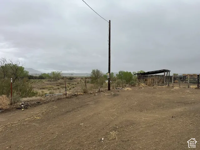 Expansive rural landscape featuring a dirt road, sparse vegetation, and a distant mountain range