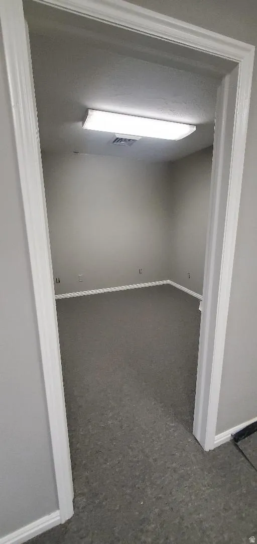 Interior room featuring neutral wall paint, white baseboards, and dark gray carpeting
