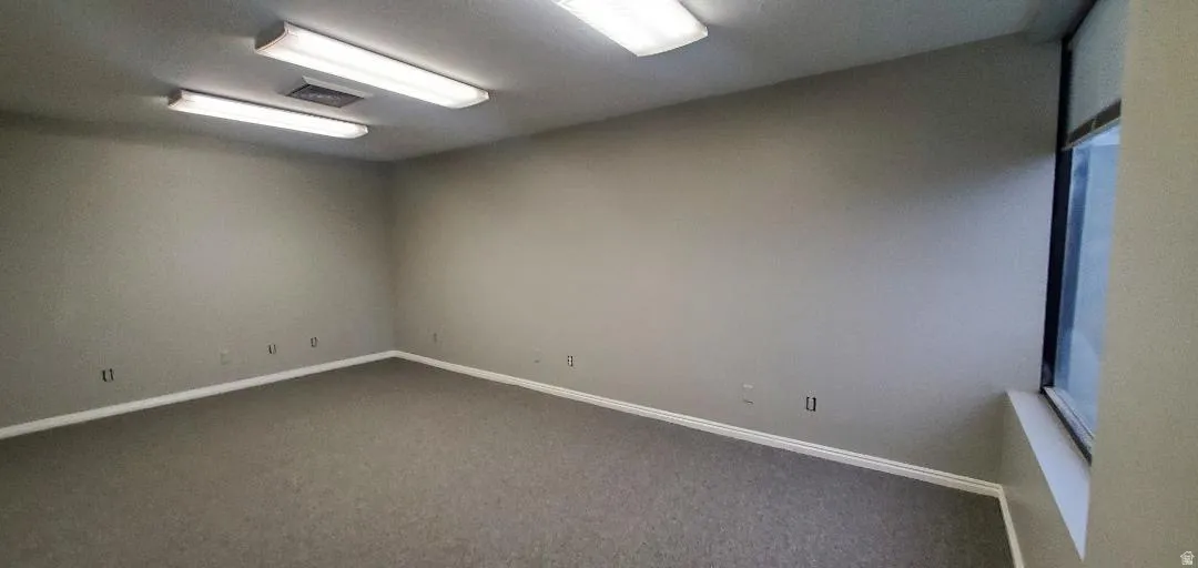 Spacious room featuring neutral-toned walls and grey carpeting
