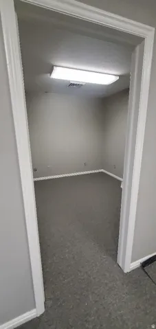 Interior room featuring neutral wall paint, white baseboards, and dark gray carpeting