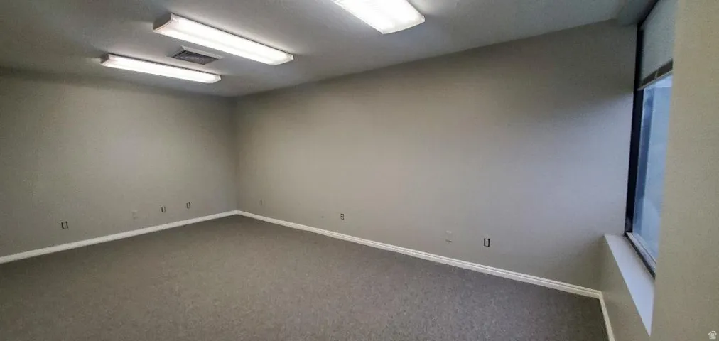 Spacious room featuring neutral-toned walls and grey carpeting