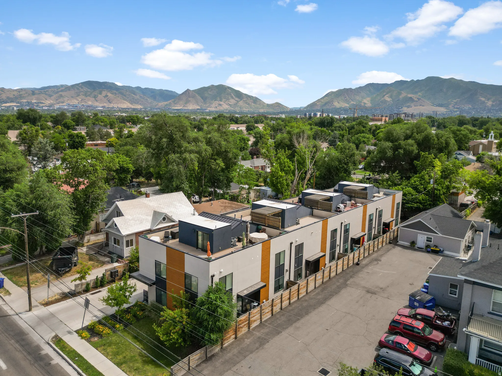 Modern townhouse row featuring flat roofs, light-colored facades with contrasting dark and wood-tone vertical accents, and individual rooftop patios
