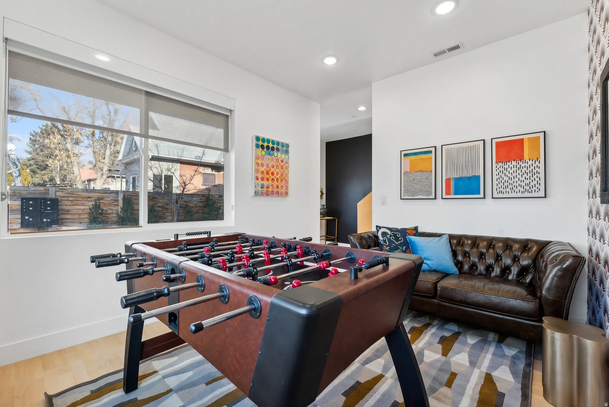 Spacious room featuring wood-finish flooring, recessed lighting, and large windows with roller shades