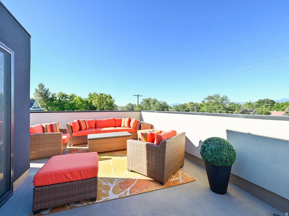 Expansive rooftop deck featuring a stucco exterior wall, a low privacy wall, and concrete flooring
