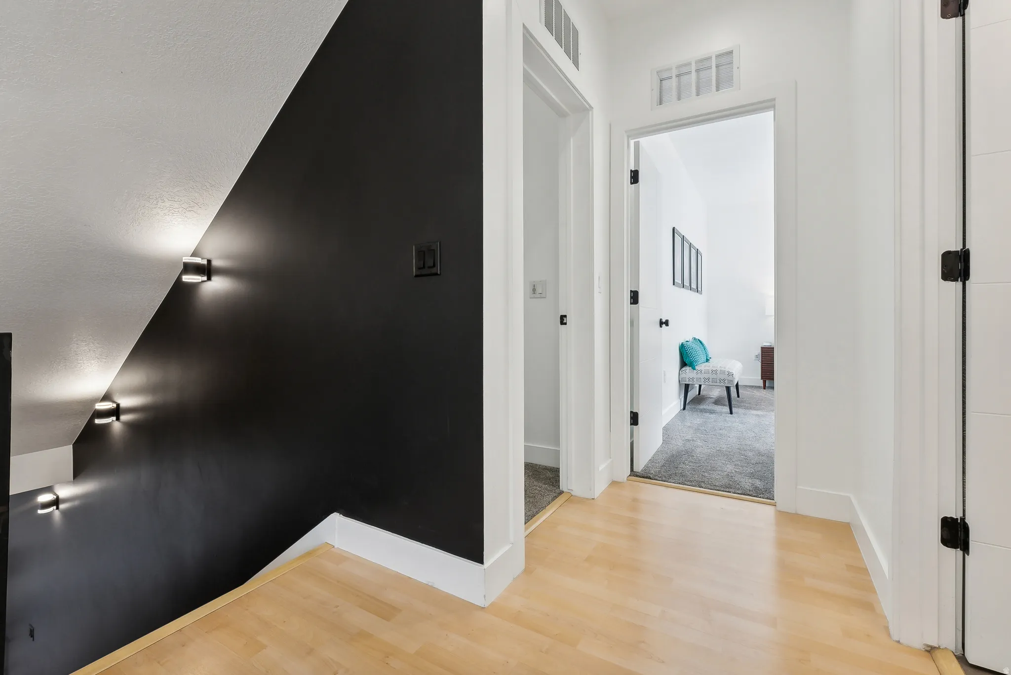 Hardwood-finish flooring extending through a hallway with white trim and black door hardware