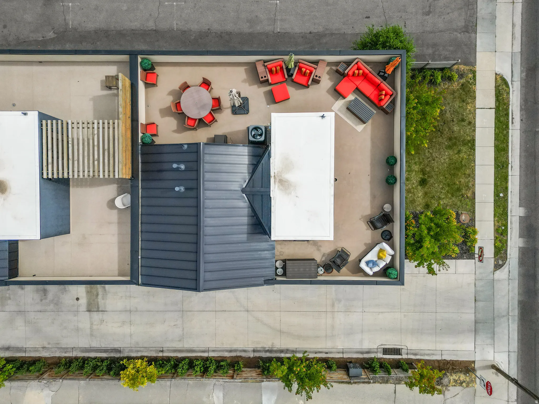 Expansive rooftop deck featuring a large patio area, dark metal roofing, and a privacy fence