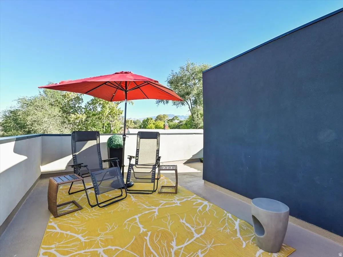 Rooftop patio with a concrete surface, low perimeter walls, and a prominent dark stucco exterior wall