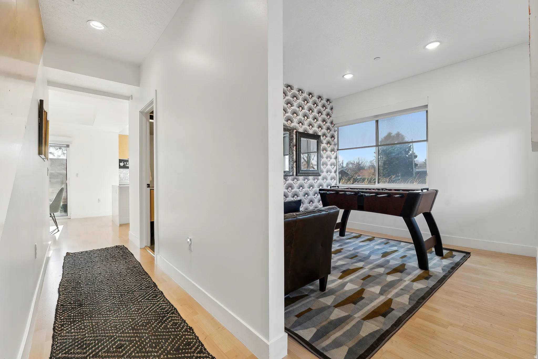 Bright interior space with light wood-finish flooring, recessed lighting, and a large window providing natural light