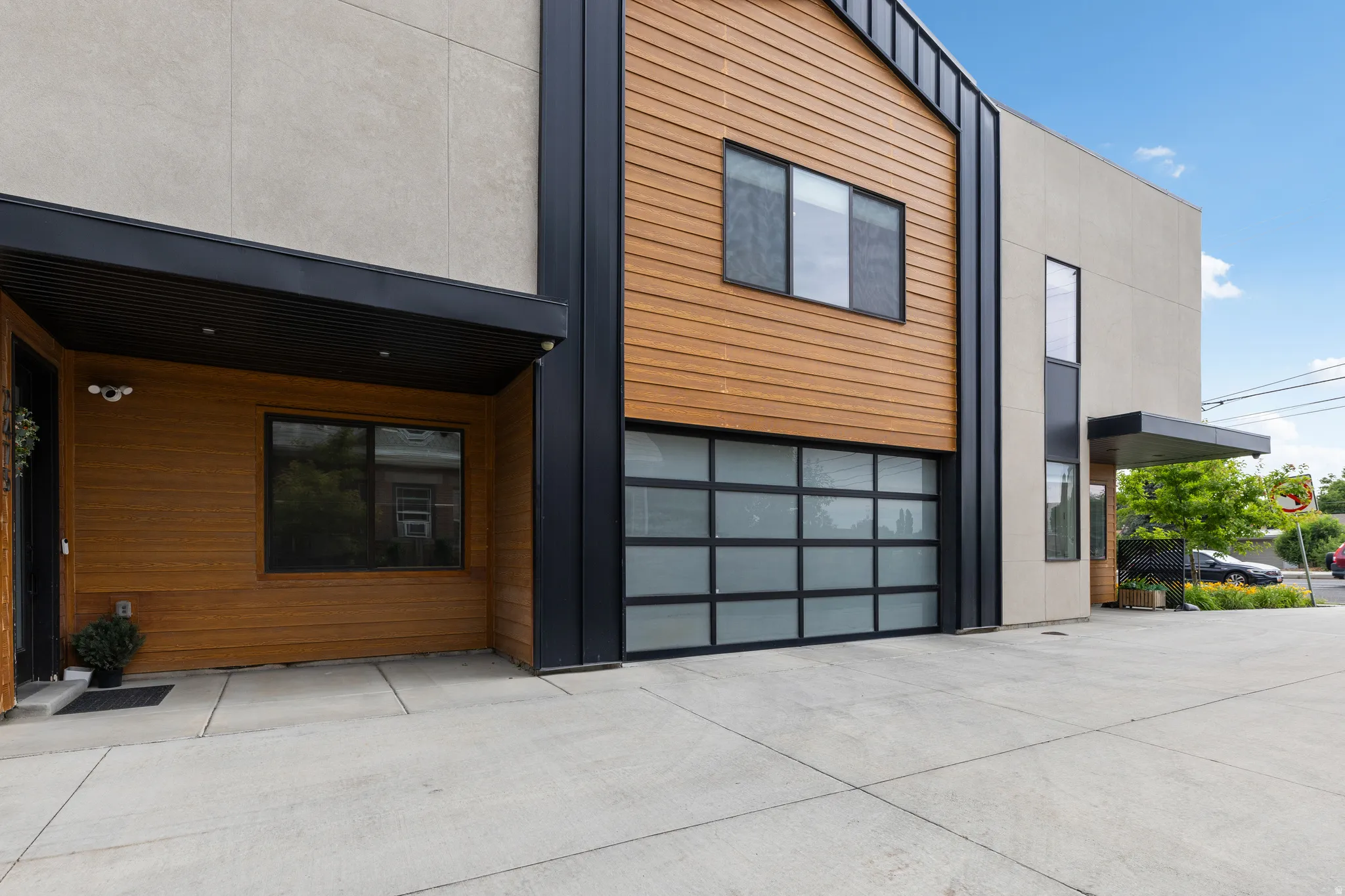 Modern exterior with wood-finish siding, light-toned stucco, and black architectural accents