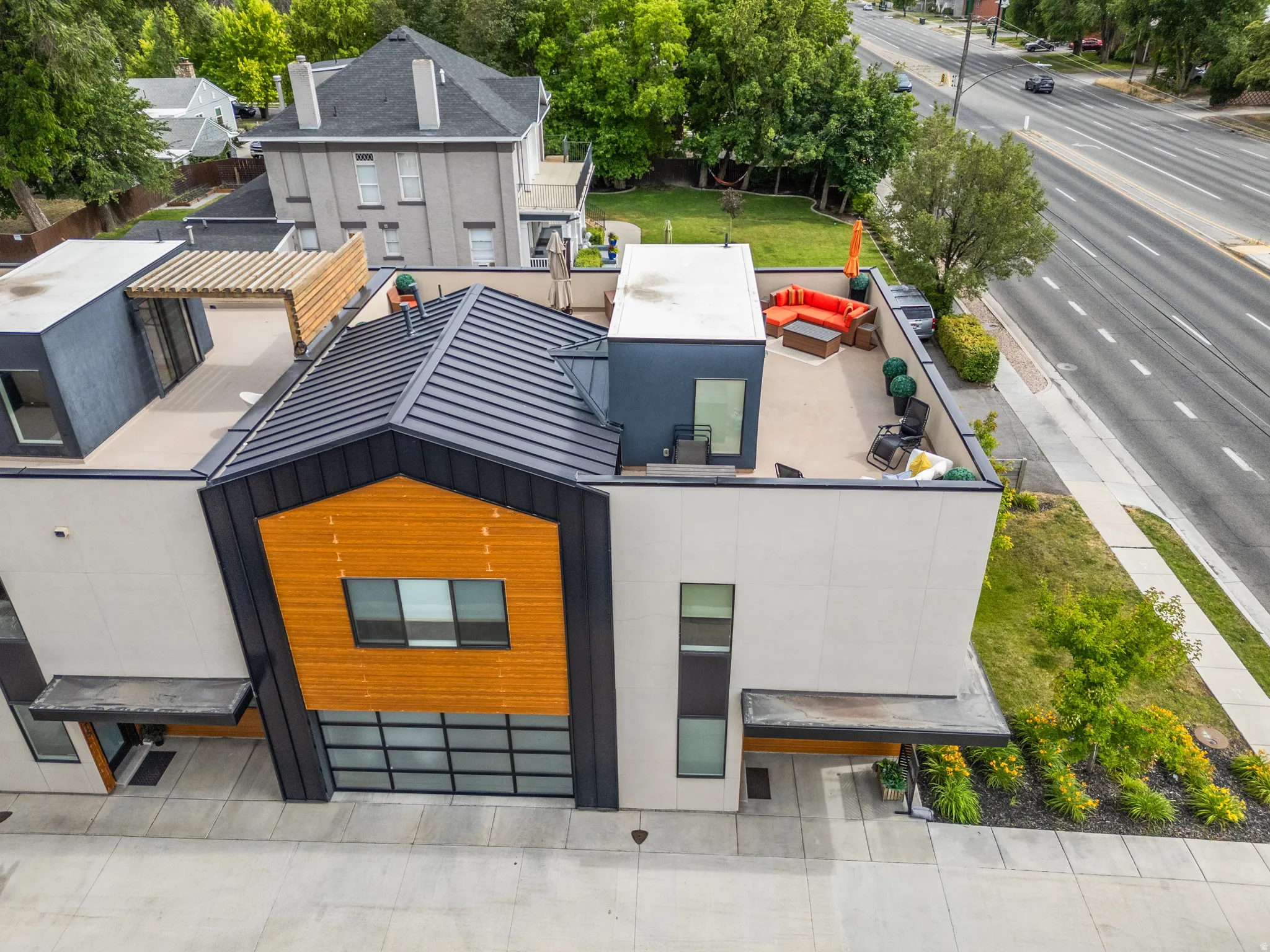 Contemporary townhome exterior featuring an angular metal roof, wood-finish paneling, and a large rooftop deck