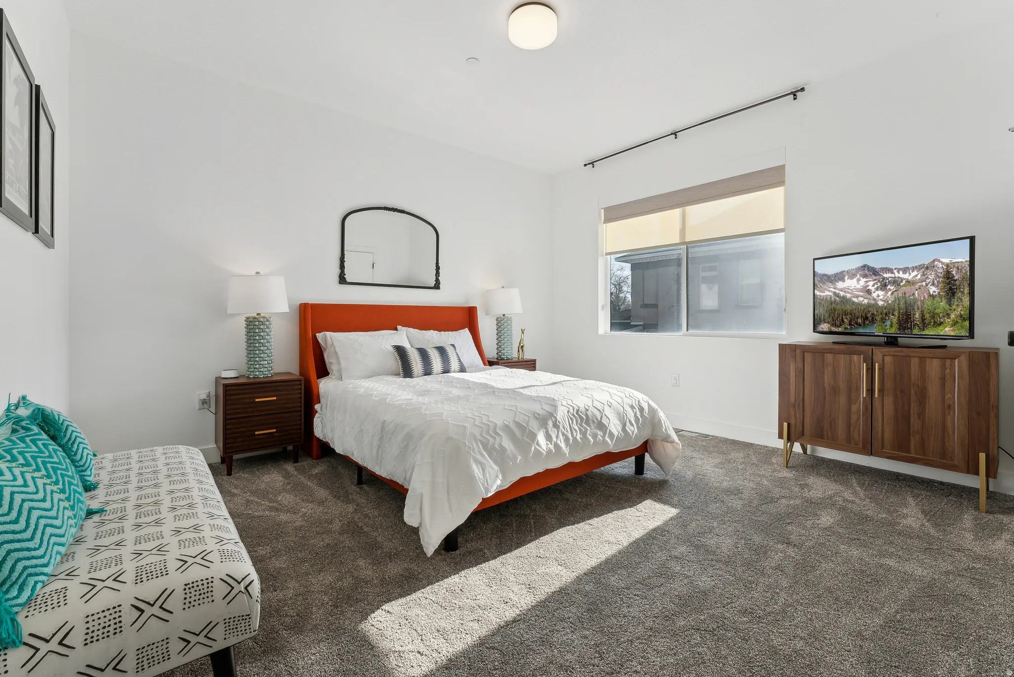 Carpeted room featuring a large window with roller shades, a ceiling-mounted light fixture, and white painted walls