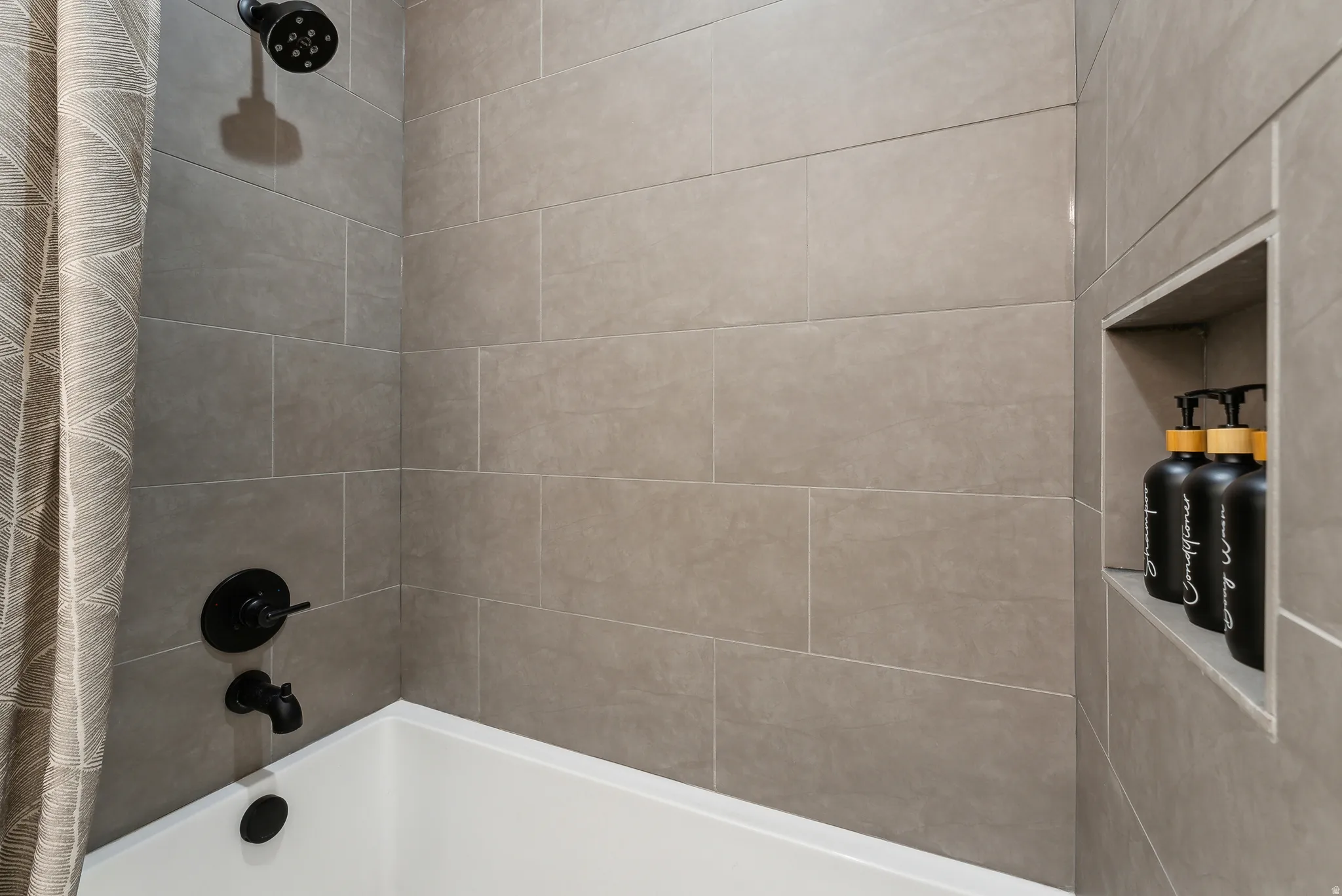 Subway tile surround featuring a built-in niche, matte black fixtures, and a white soaking tub