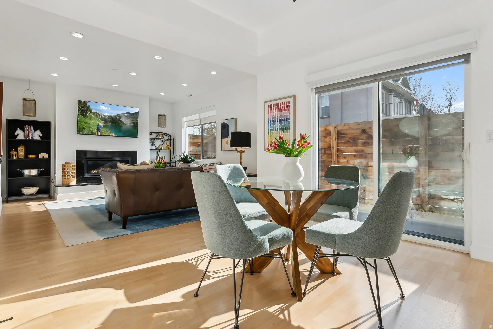 Open-concept living space featuring wood-finish flooring, recessed lighting, and a modern fireplace with a dark surround