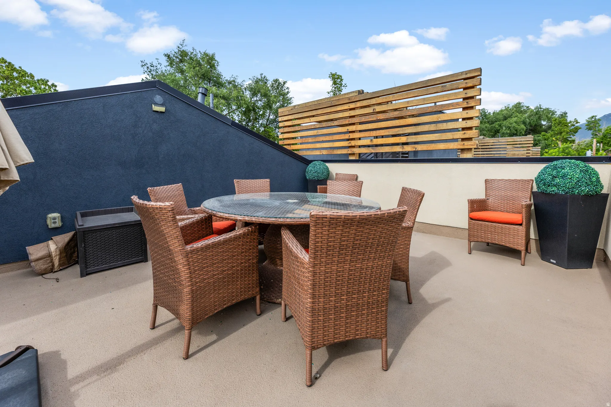 Spacious rooftop deck featuring a stucco wall, slatted wood privacy screen, and a durable concrete surface