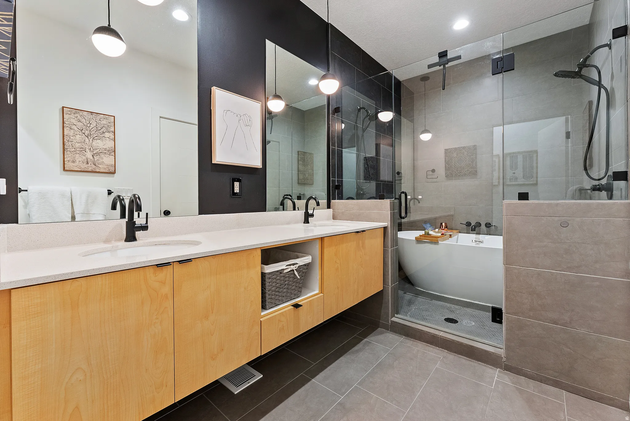 Bathroom featuring a floating double vanity with light wood-finish cabinetry and white countertops, set against a dark accent wall