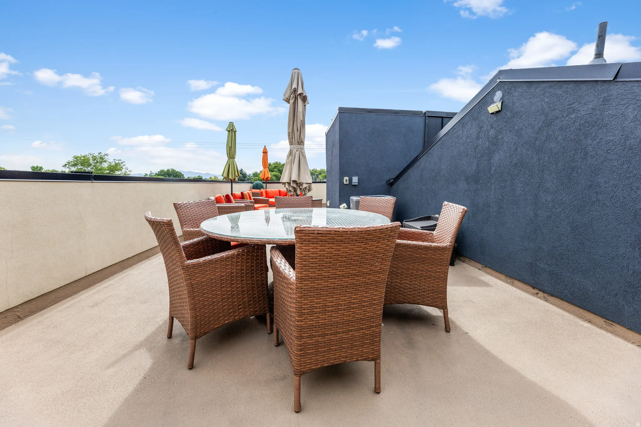 Expansive rooftop deck featuring a stucco parapet wall, concrete flooring, and a dark stucco exterior wall