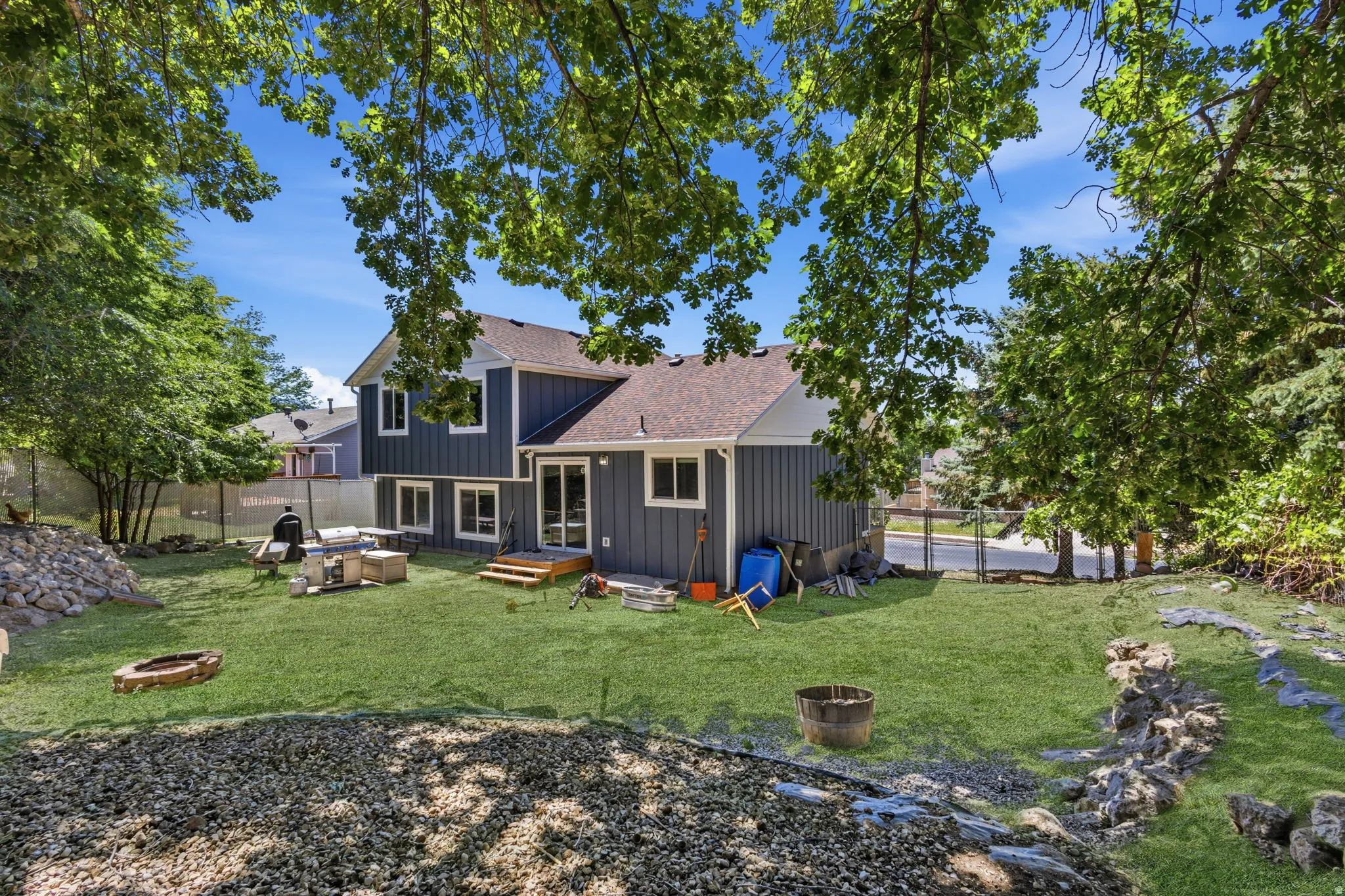Rear exterior featuring a spacious lawn, wood deck, and multiple windows