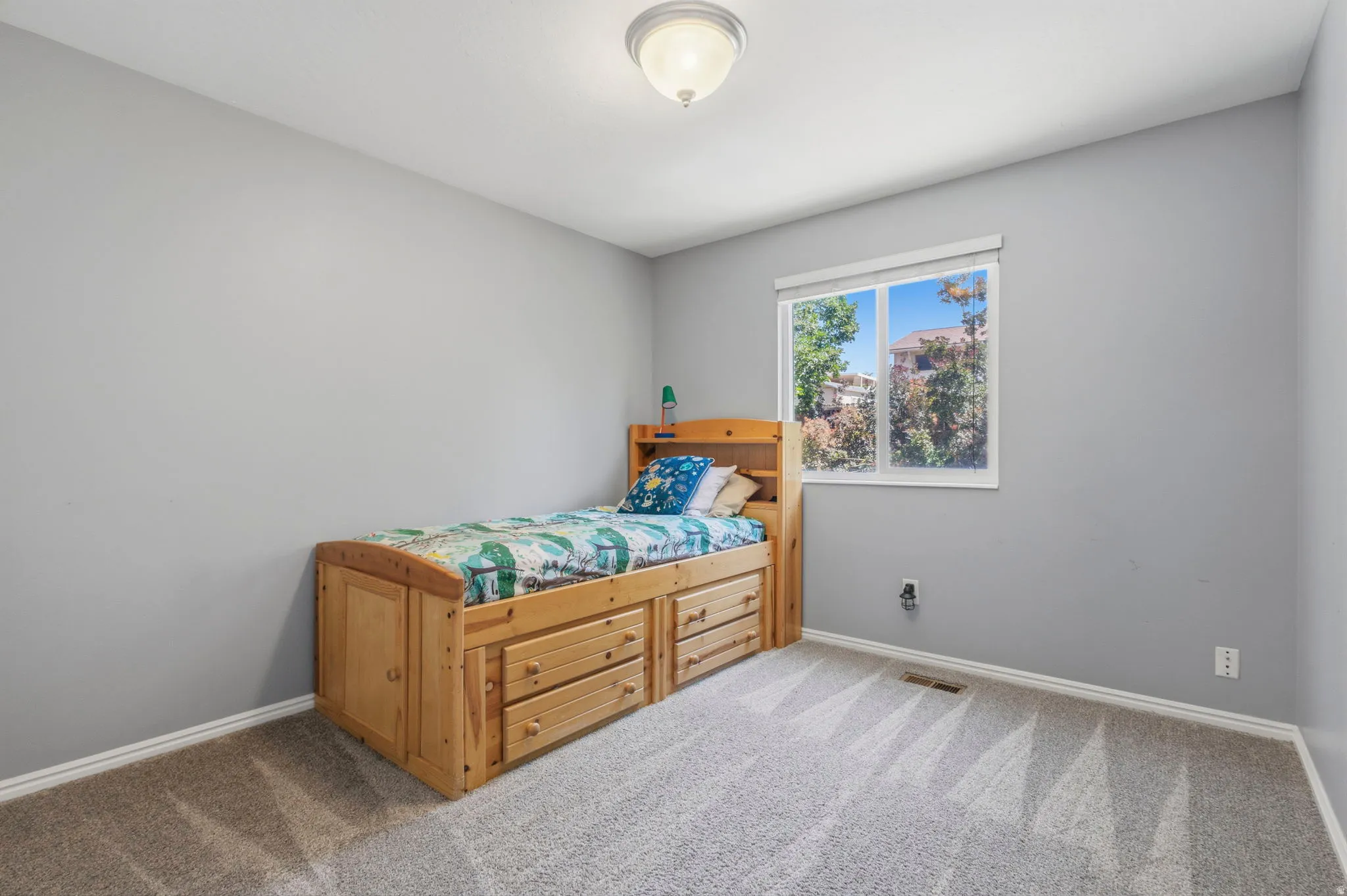 Carpeted room with a single window and light gray walls