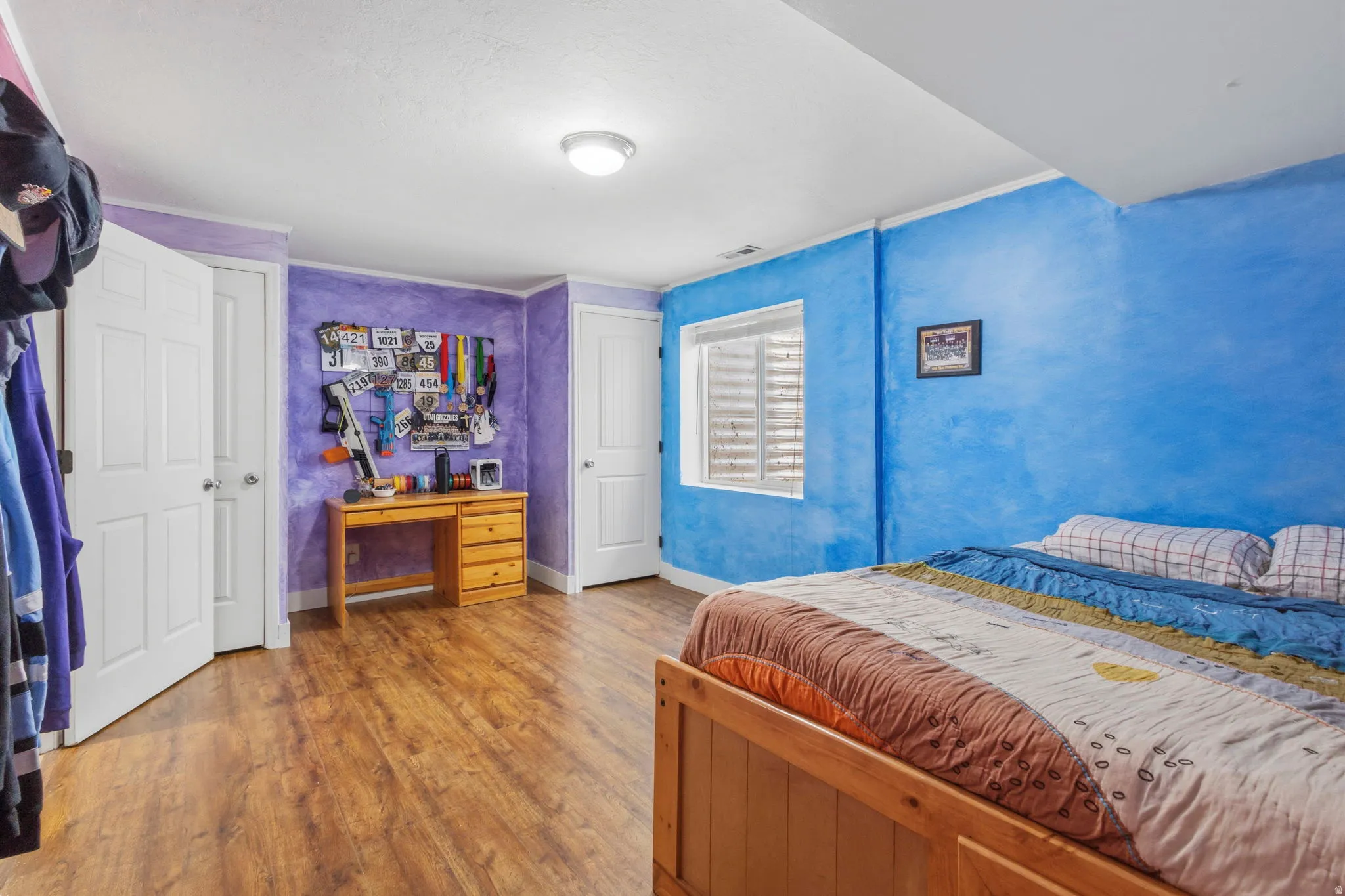 Room featuring wood-finish flooring, white trim, and a window with blinds