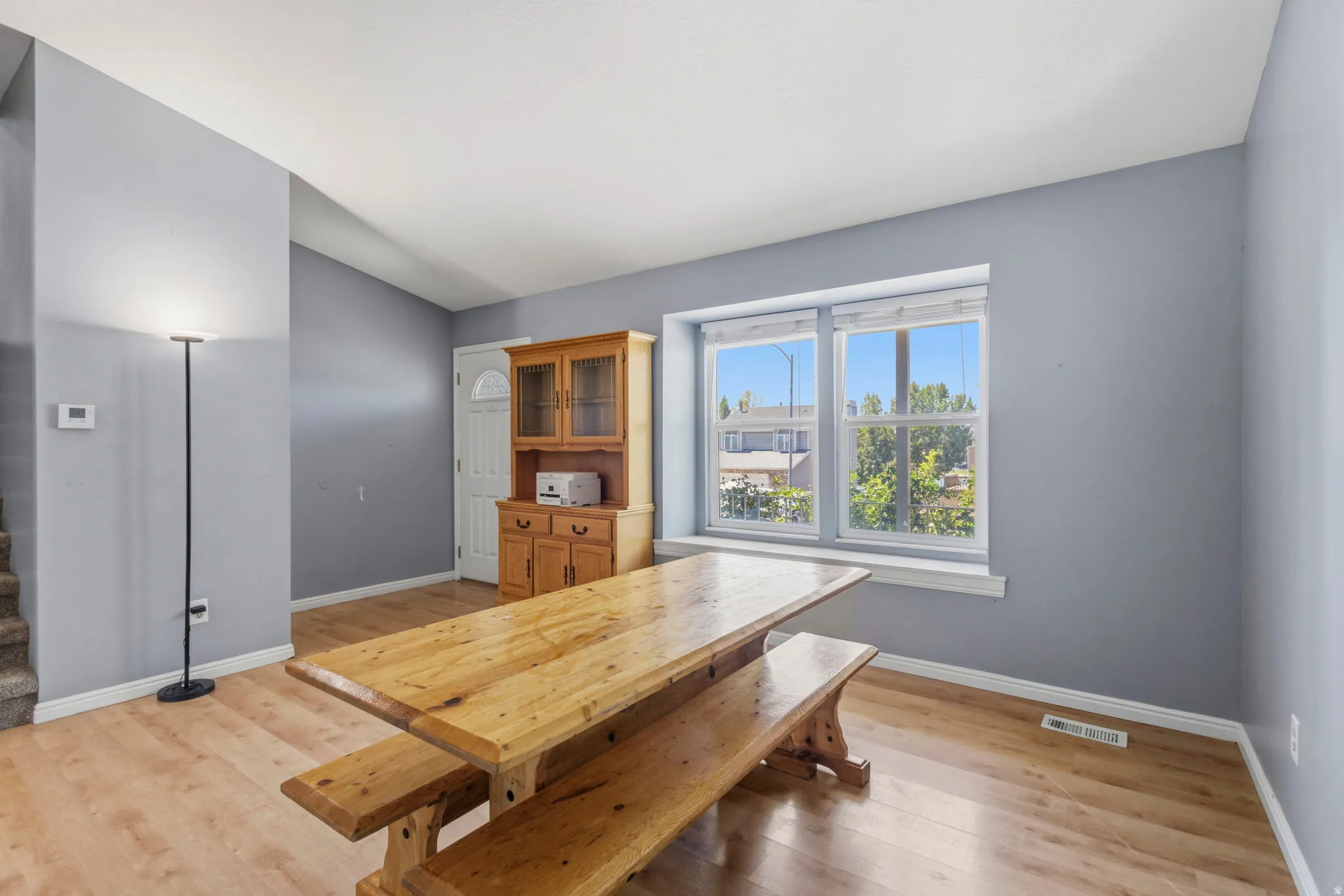 Spacious room with wood-finish flooring, a bright window, and light gray walls