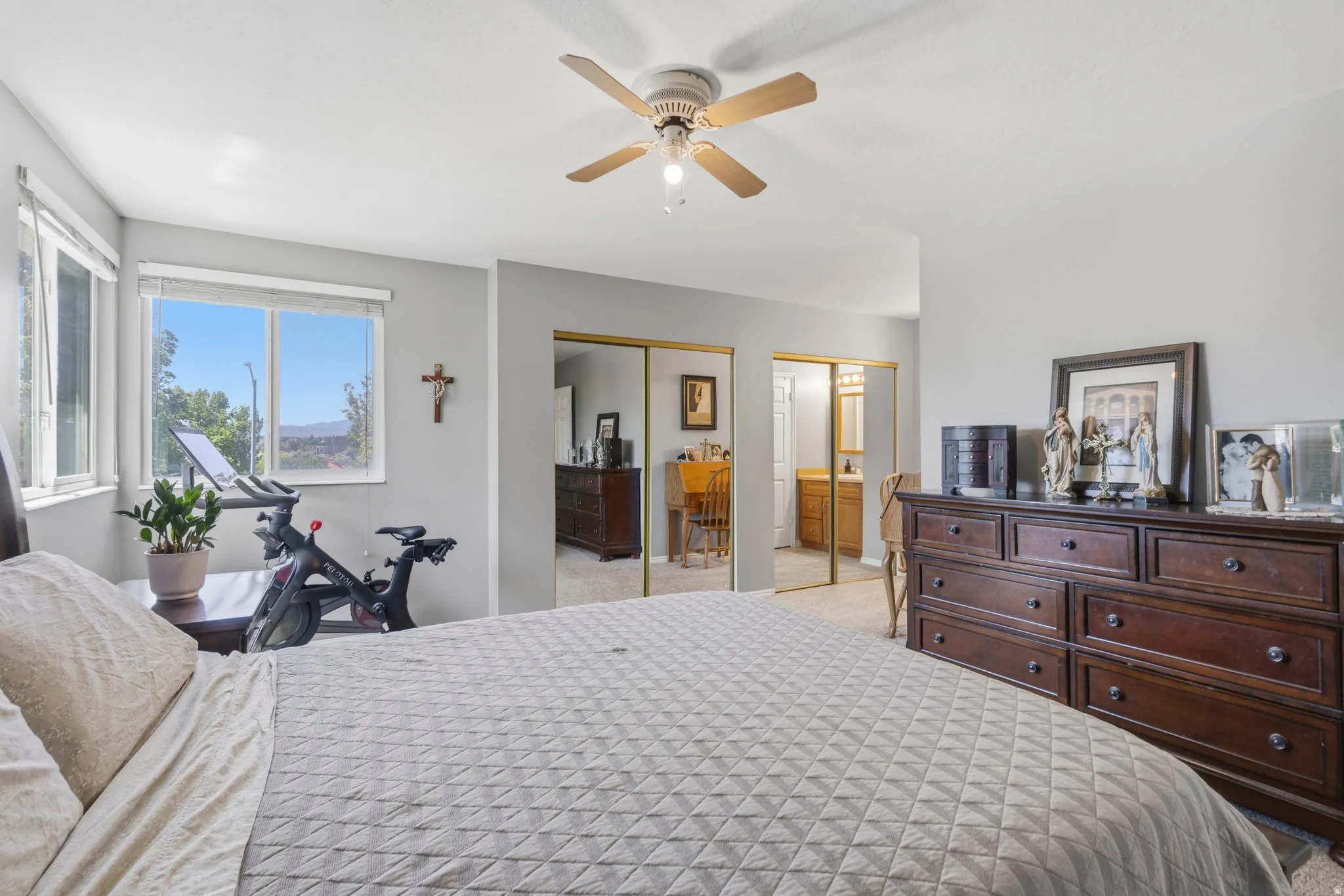 Bedroom featuring a ceiling fan, multiple windows with natural light, and two mirrored sliding closet doors