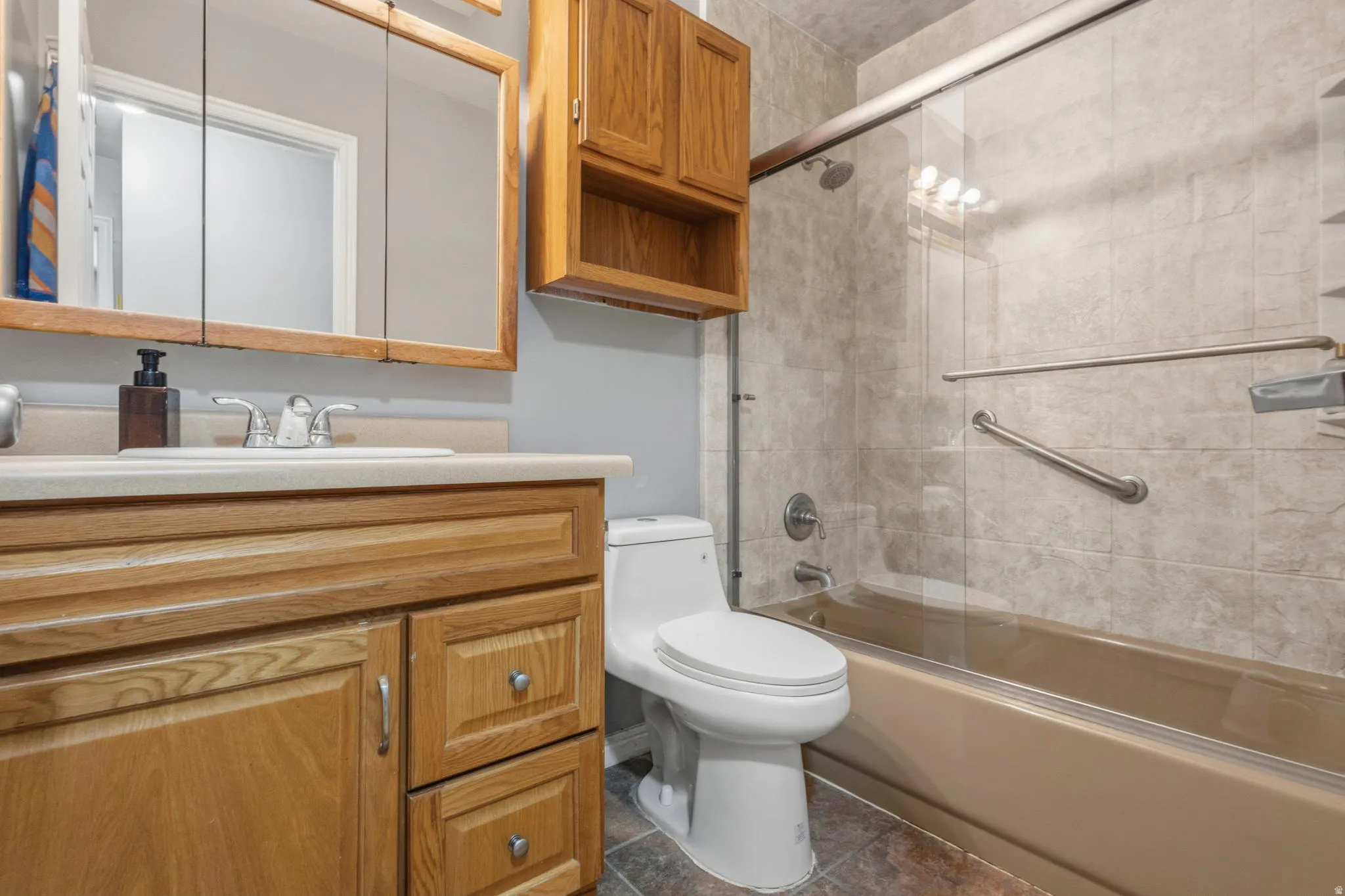 Bathroom featuring a light wood-finish vanity with an integrated sink and chrome faucet, a matching medicine cabinet, and an overhead wooden storage cabinet