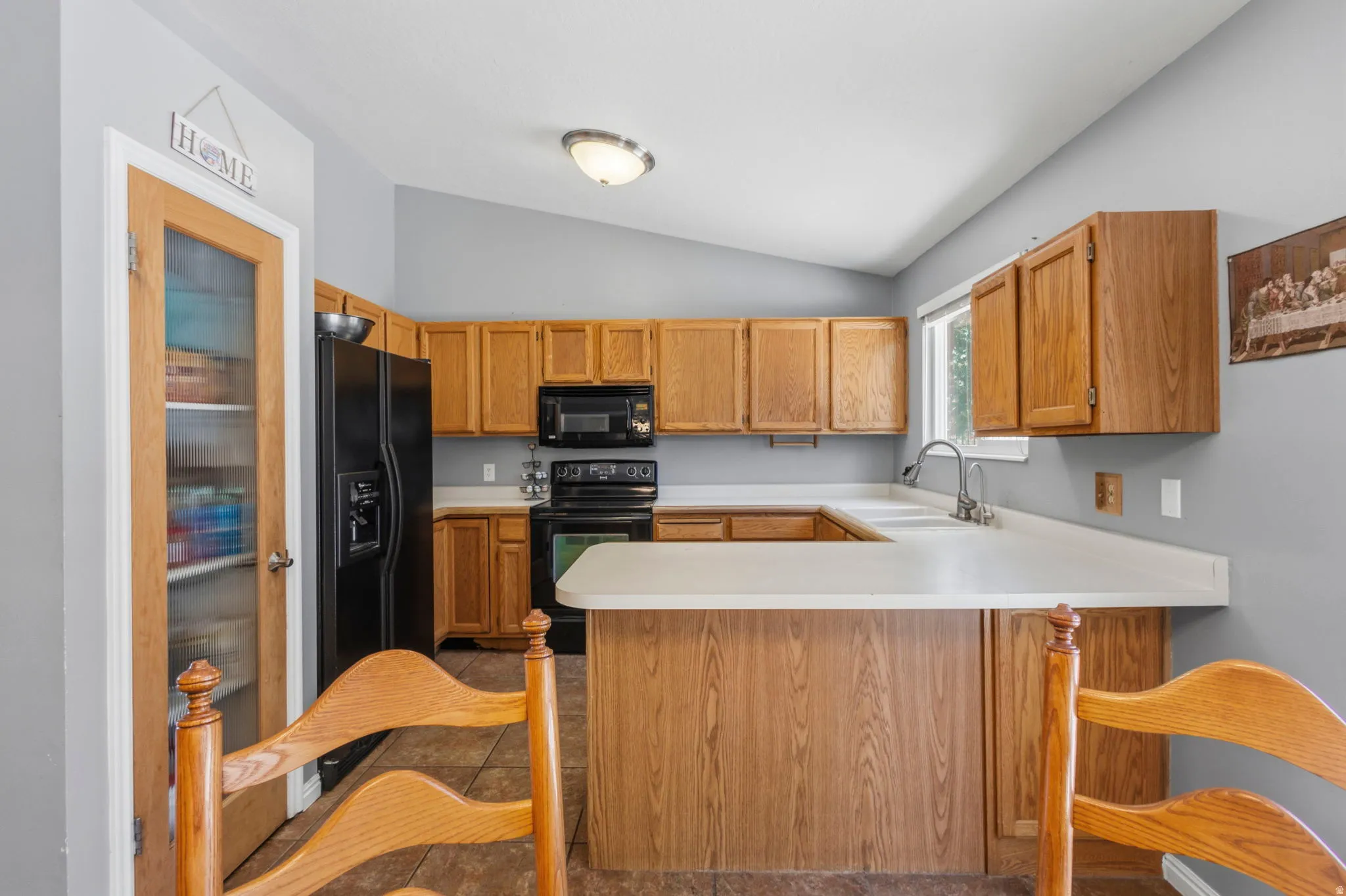 Well-appointed kitchen featuring wood-finish cabinetry, light countertops, and a black appliance suite