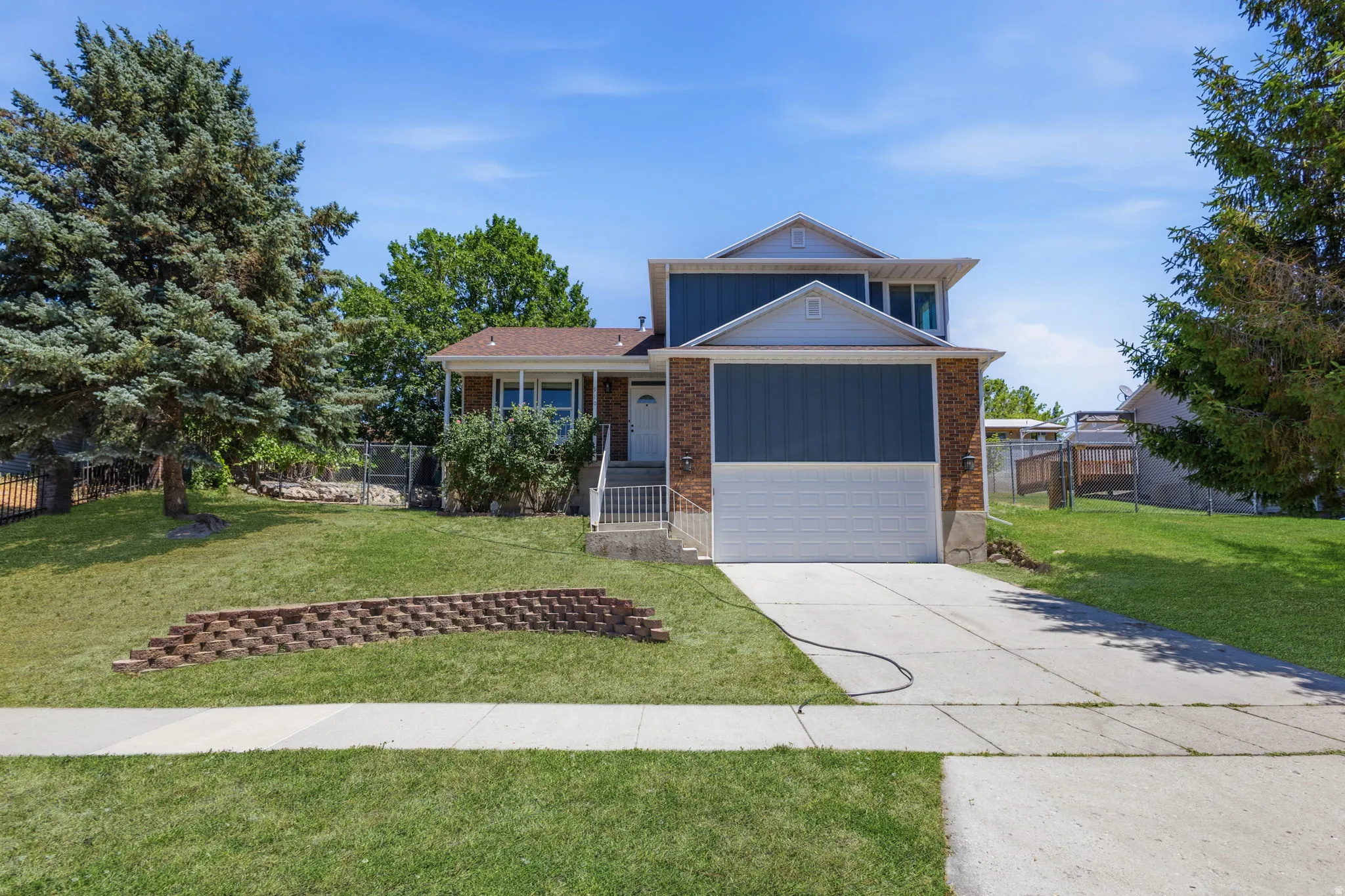 Two-story residence featuring a blue siding and brick exterior with a white trim