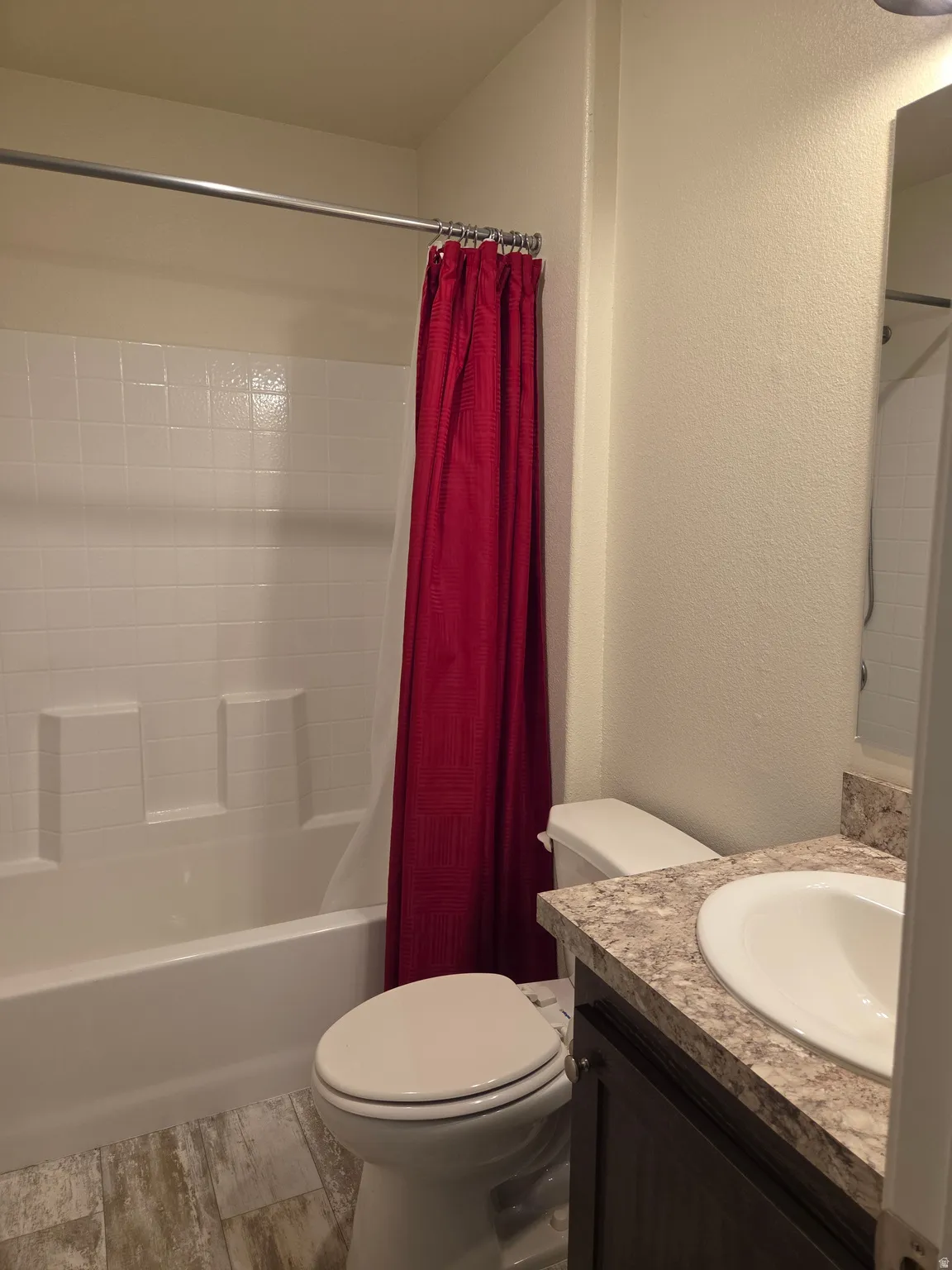 Bathroom featuring a white tub and shower surround, a white toilet, and a vanity