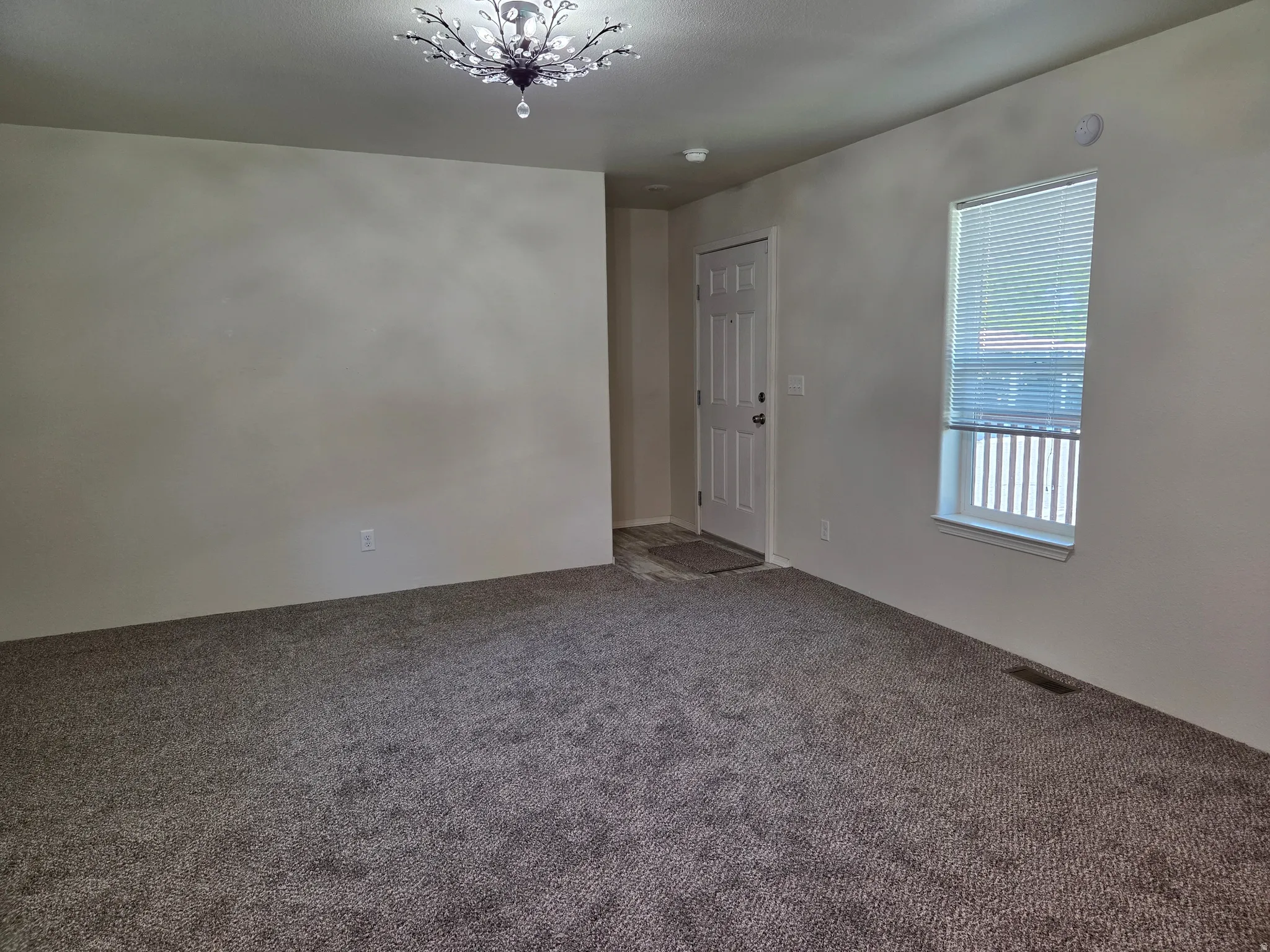 Neutral-toned carpet flooring, light wall paint, and a decorative ceiling light fixture
