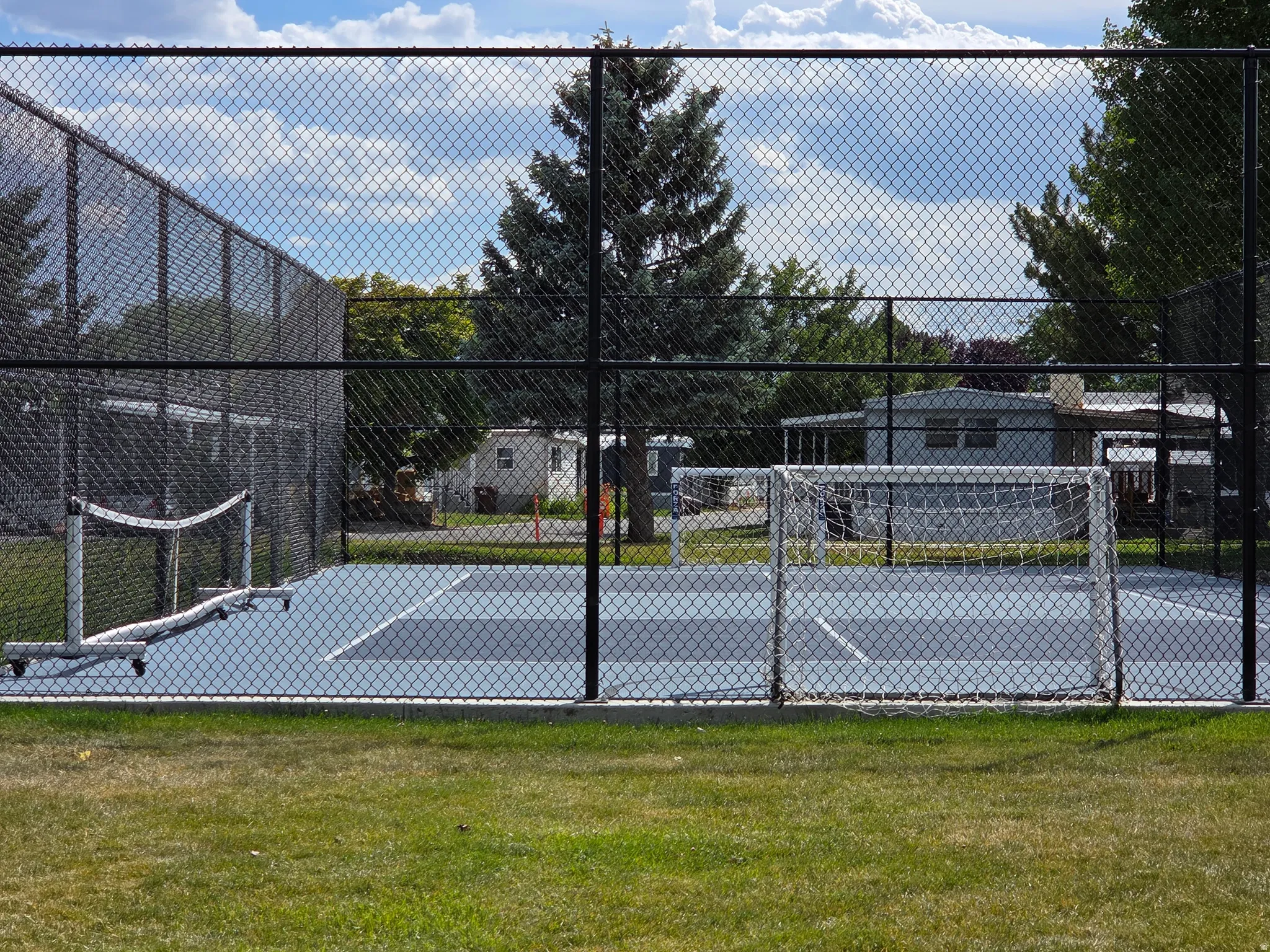 Multi-sport court with light blue and dark blue playing surfaces, enclosed by chain-link fencing